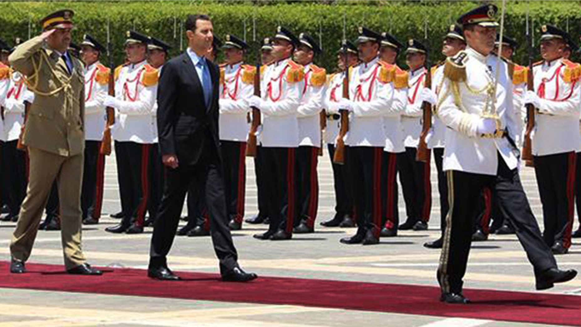July 16, 2014: In this photo released by the Syrian official news agency SANA, Syria's President Bashar Assad, center, reviews the honor guard upon his arrival at the presidential palace to take the oath of office for his third, seven-year term, in Damascus, Syria.