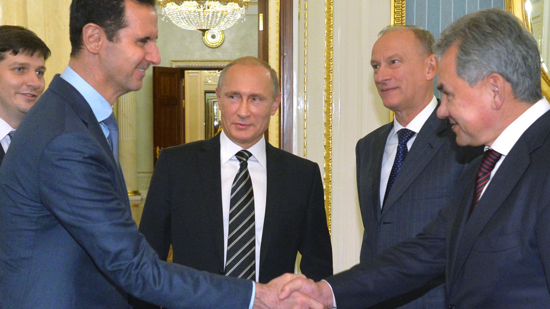 Assad, second left, shakes hand with Shoigu as Russian President Vladimir Putin, center, looks on, in October 2015.