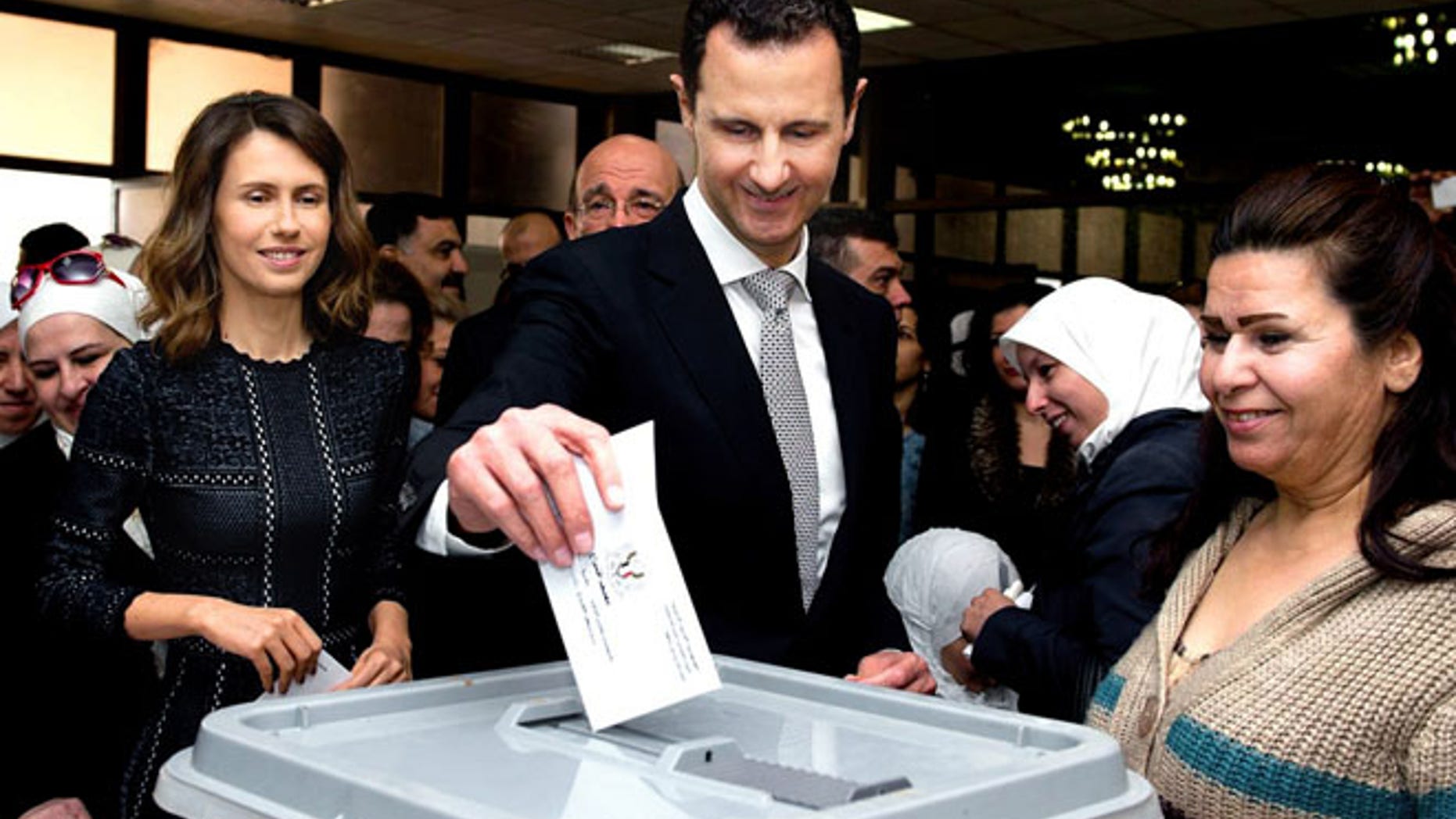 APRIL 13: This photo released on the official Facebook page of Syrian Presidency, shows Syrian President Bashar Assad casting his ballot in the parliamentary elections, as his wife Asma, left, is standing next to him, in Damascus.