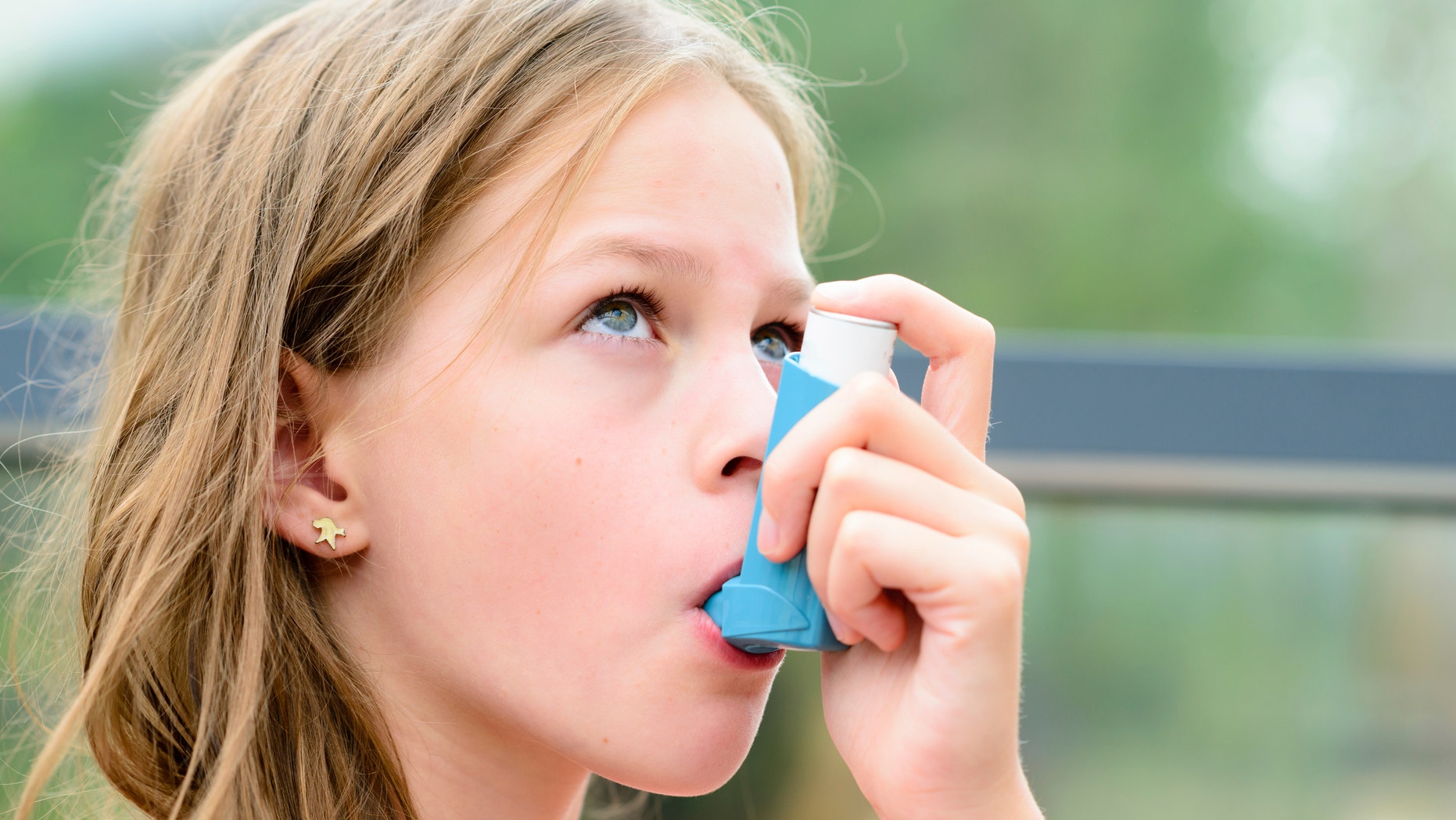 Girl having asthma using the asthma inhaler for being healthy - shallow depth of field - asthma allergy concept