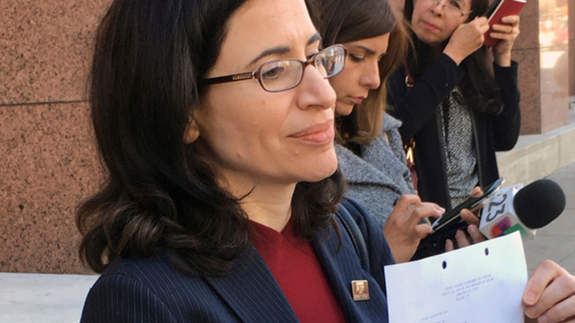Dallas immigration attorney Fatma Marouf holds up a bond order in front of the federal building after leaving immigration court in Dallas, Thursday, March 2, 2017, from a federal immigration judge for Sara Beltran Hernandez, a Salvadoran woman seeking asylum. An immigration judge has granted bond to Hernandez so she can leave a detention facility to seek treatment for a brain tumor. (AP Photo/Claudia Lauer)