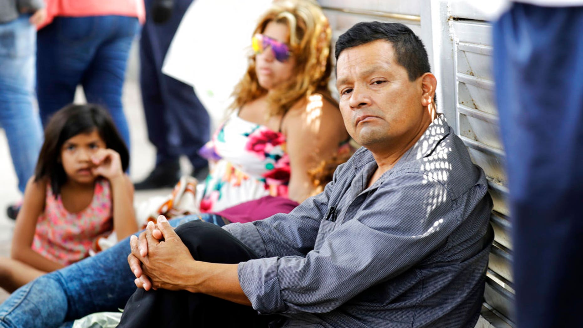Ruben Prado, right, an immigrant from Guatemala seeking asylum in the United States, waits on the Gateway International Bridge along with a family from Honduras, in Matamoros, Mexico on Sunday, June 24, 2018. Prado arrived at the bridge today after traveling for 20 days. (AP Photo/David J. Phillip)
