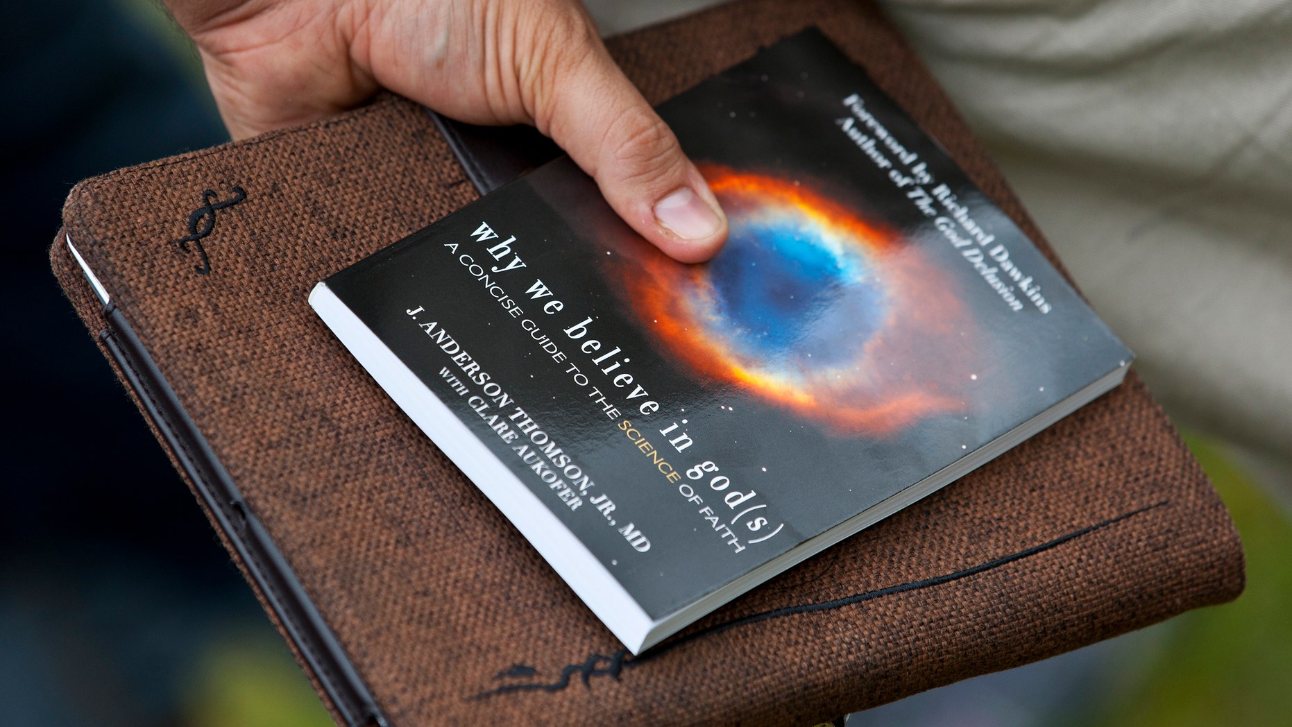 A supporter talks to Richard Dawkins, a well-known atheist and best-selling author, while holding a copy of his book during an atheist-themed festival at Fort Bragg army base in North Carolina.