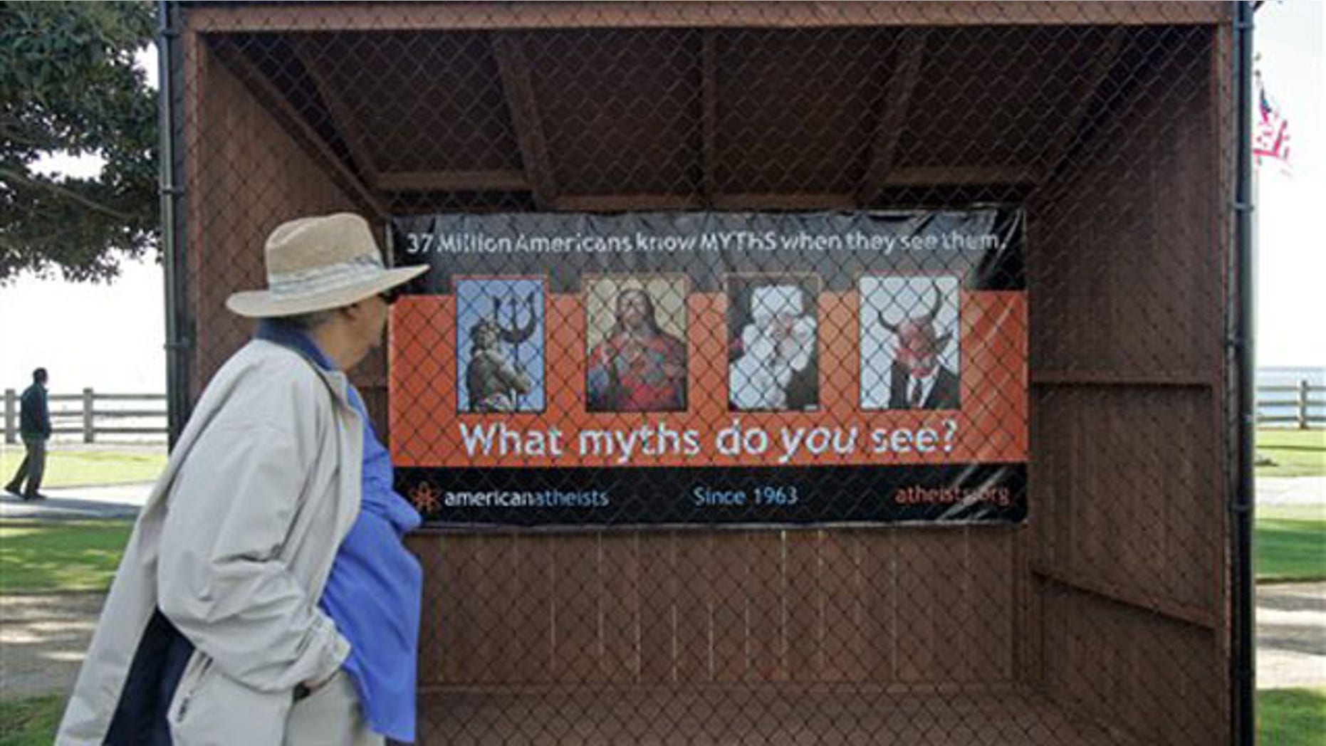 A woman walks past a sign displaying an Atheist message along Ocean Avenue at Palisades Park in Santa Monica, Calif. Tuesday, Dec. 13, 2011.