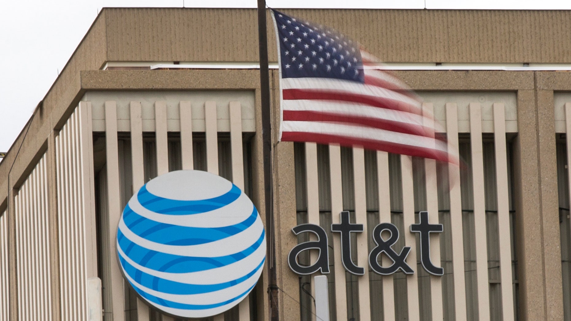 File photo - An AT&T Logo is pictured as a U.S. flag flutters in the foreground in Pasadena, Calif., Jan. 26, 2015. (REUTERS/Mario Anzuoni)