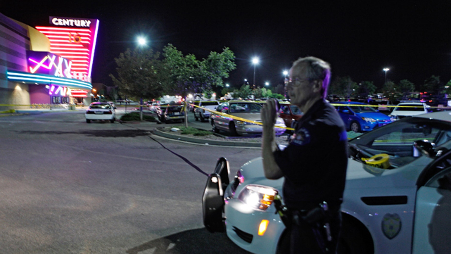 Friday, July 20, 2012: An Aurora Police officer talks on his radio outside of the Century 16 theater where as many as 14 people were killed and many injured during a shooting in Aurora, Colo. (AP Photo/Ed Andrieski)