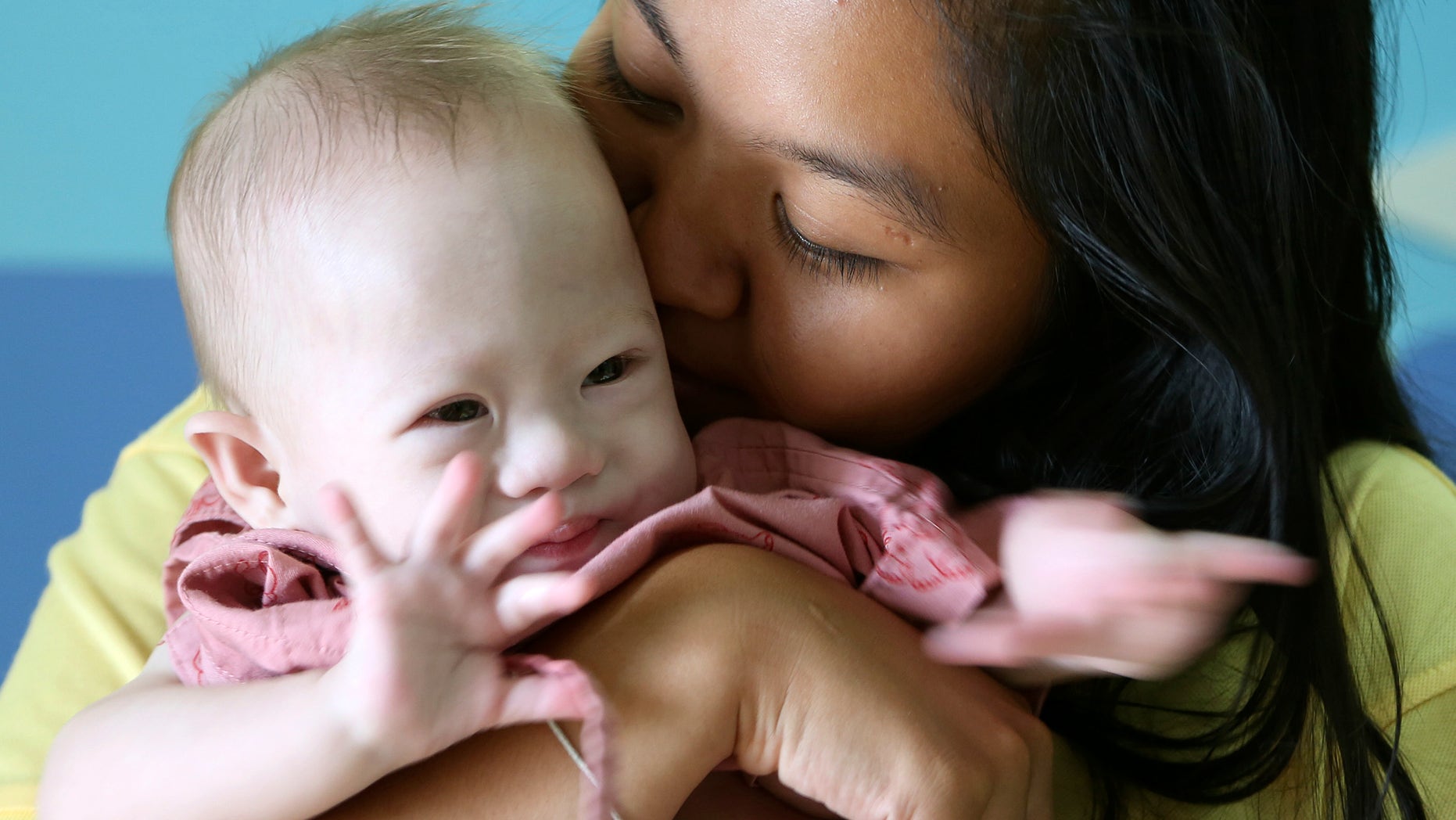 FILE - In this Aug. 3, 2014 file photo, Pattaramon Chanbua kisses her baby boy Gammy at a hospital in Chonburi province, southeastern Thailand. The newborn Down syndrome baby left by his Australian biological father with his poor surrogate mother in Thailand was one of several cases of surrogate children abandoned because of defects, an expert told a parliamentary inquiry on Thursday, Feb. 4, 2016. The high-profile case of baby Gammy prompted the Thai government to ban surrogacy in 2014, and an Australian parliamentary committee launched a review of Australia's laws that prohibit commercial surrogacy. (AP Photo/Apichart Weerawong, File)