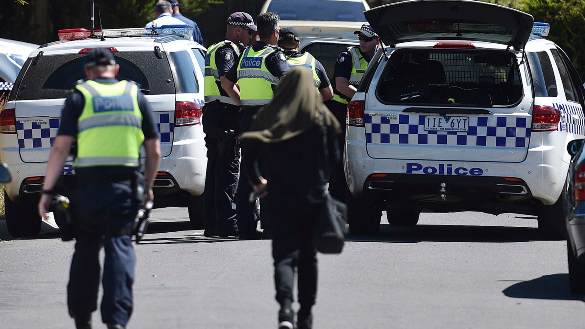 Police accompany a woman as they attend the scene where a house was raided at Meadow Heights in Melbourne, Australia, Friday, Dec. 23, 2016.