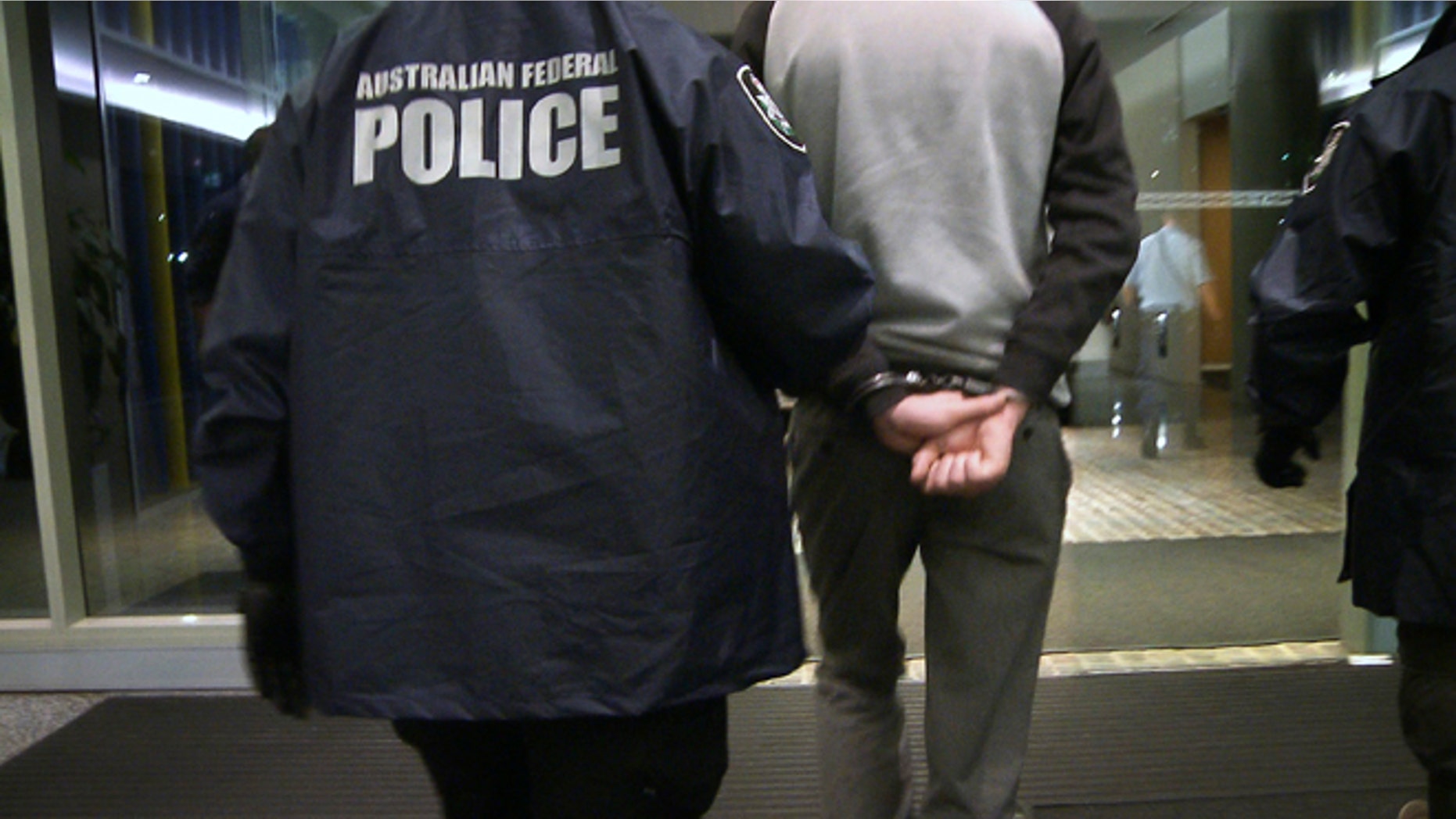 April 23, 2013: In this photo provided by the Australian Federal Police, a handcuffed man is escorted by police following his arrest on a charge of attacking and defacing a government website. The Australian man, who police say has claimed to be a high-level member of international hacking collective Lulz Security, was charged with two counts of unauthorized modification of data to cause impairment, and one count of unauthorized access to, or modification of, restricted data.