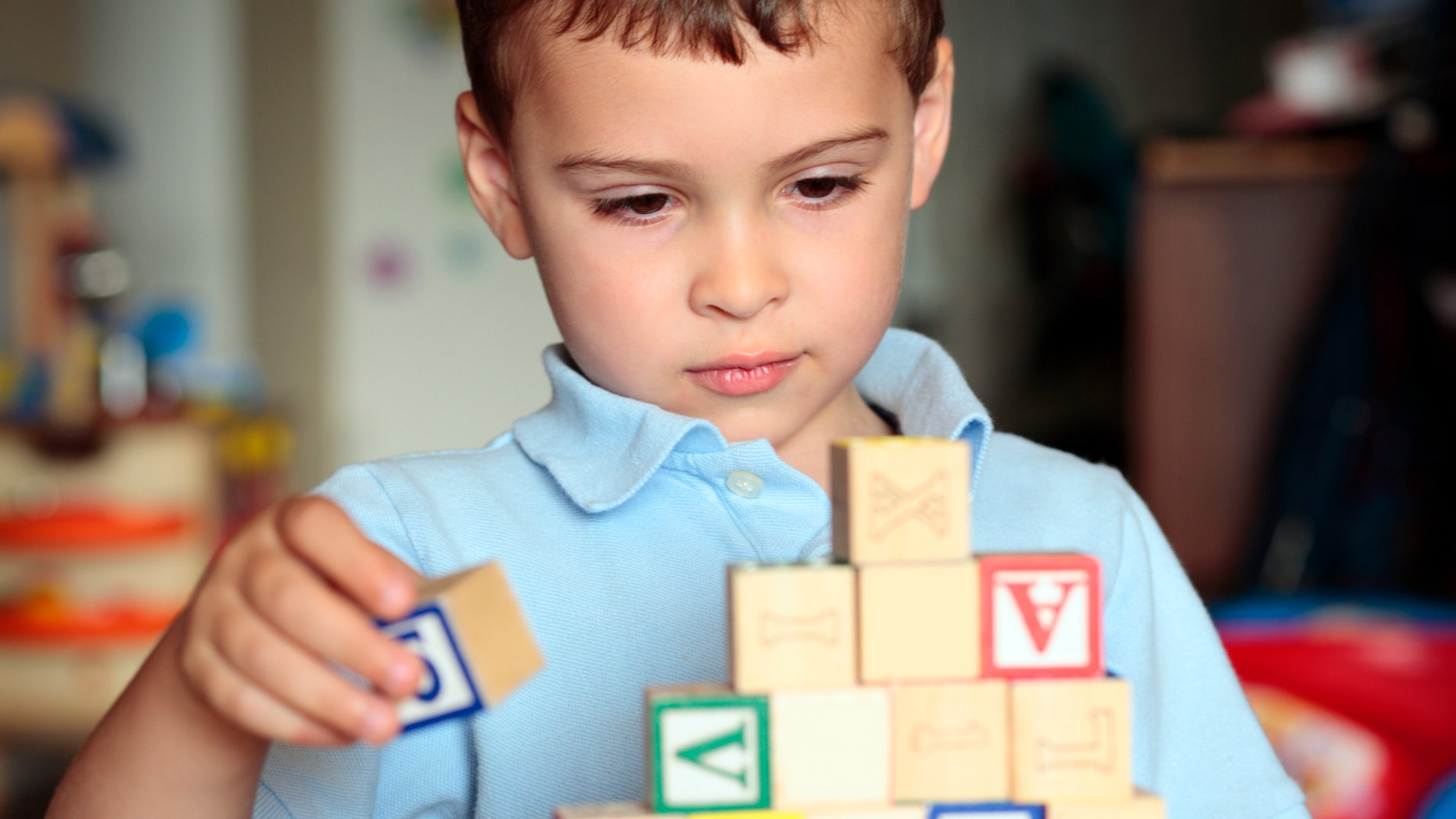Child with autism deciding where is the best place to put his block. Shall he build it higher?