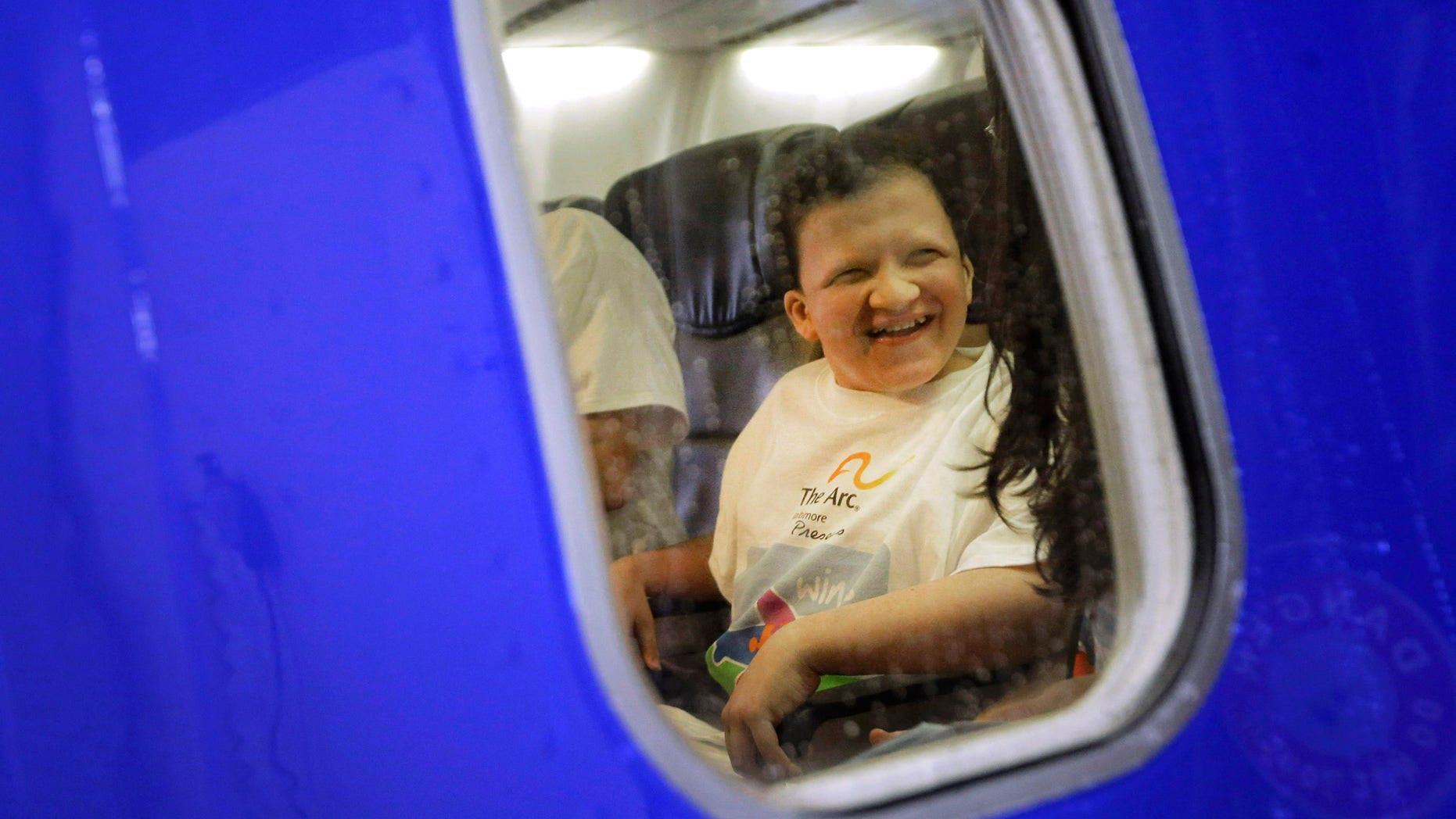 Nathaniel Epstein, 14, smiles as he sits in his seat on an airplane at the Baltimore-Washington International Thurgood Marshall Airport, Saturday, Dec. 6, 2014, in Linthicum, Md., during Wings for Autism, an airport rehearsal for children with autism spectrum disorders, their families and aviation officials. Families took part in a typical airport experience, from check-in and security to boarding a plane, with the intention of alleviating some of the stress of air travel for children with autism. (AP Photo/Patrick Semansky)