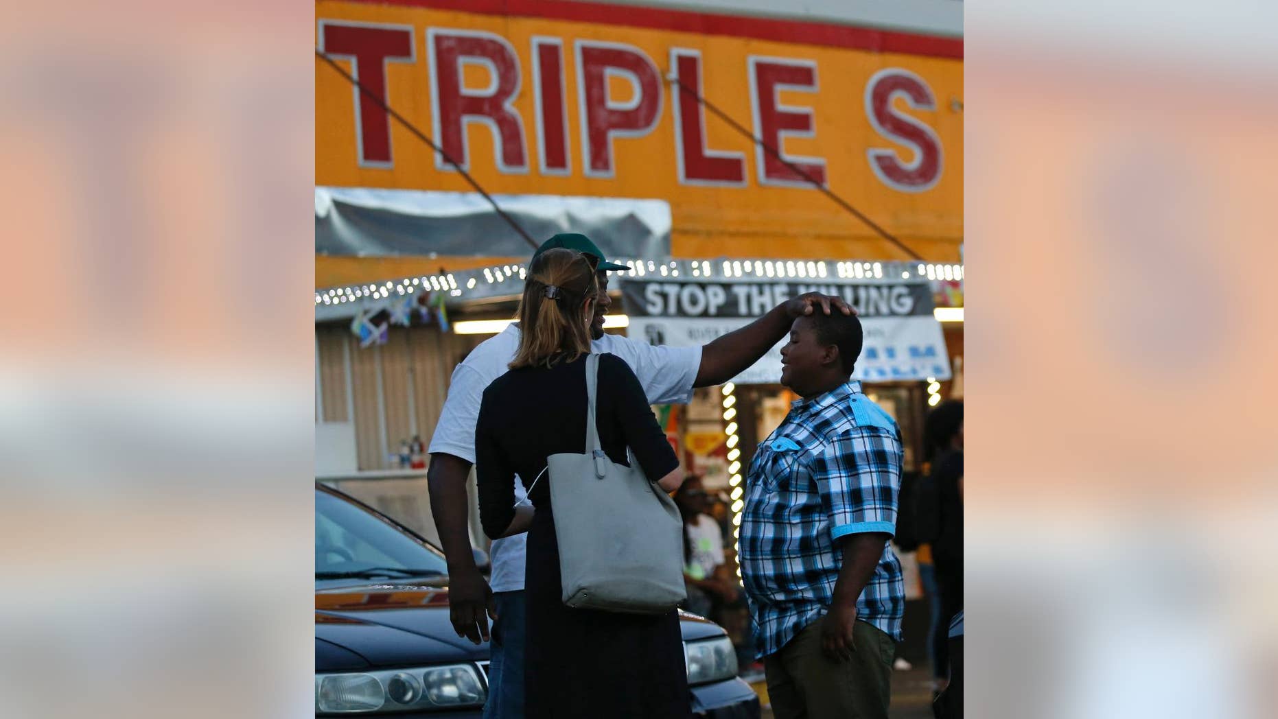 Darin Fontenette, left, football coach for Na'Quincy Pierson, son of Alton Sterling, pats Na'Quincy on the head outside the Triple S Food Mart, where Sterling was killed last year in Baton Rouge, La., Tuesday, May 2, 2017. The U.S. Justice Department has decided not to charge two white Baton Rouge police officers in the death of Sterling, whose death was captured on cell phone video, fueling protests in Louisiana's capital and beyond. (AP Photo/Gerald Herbert)