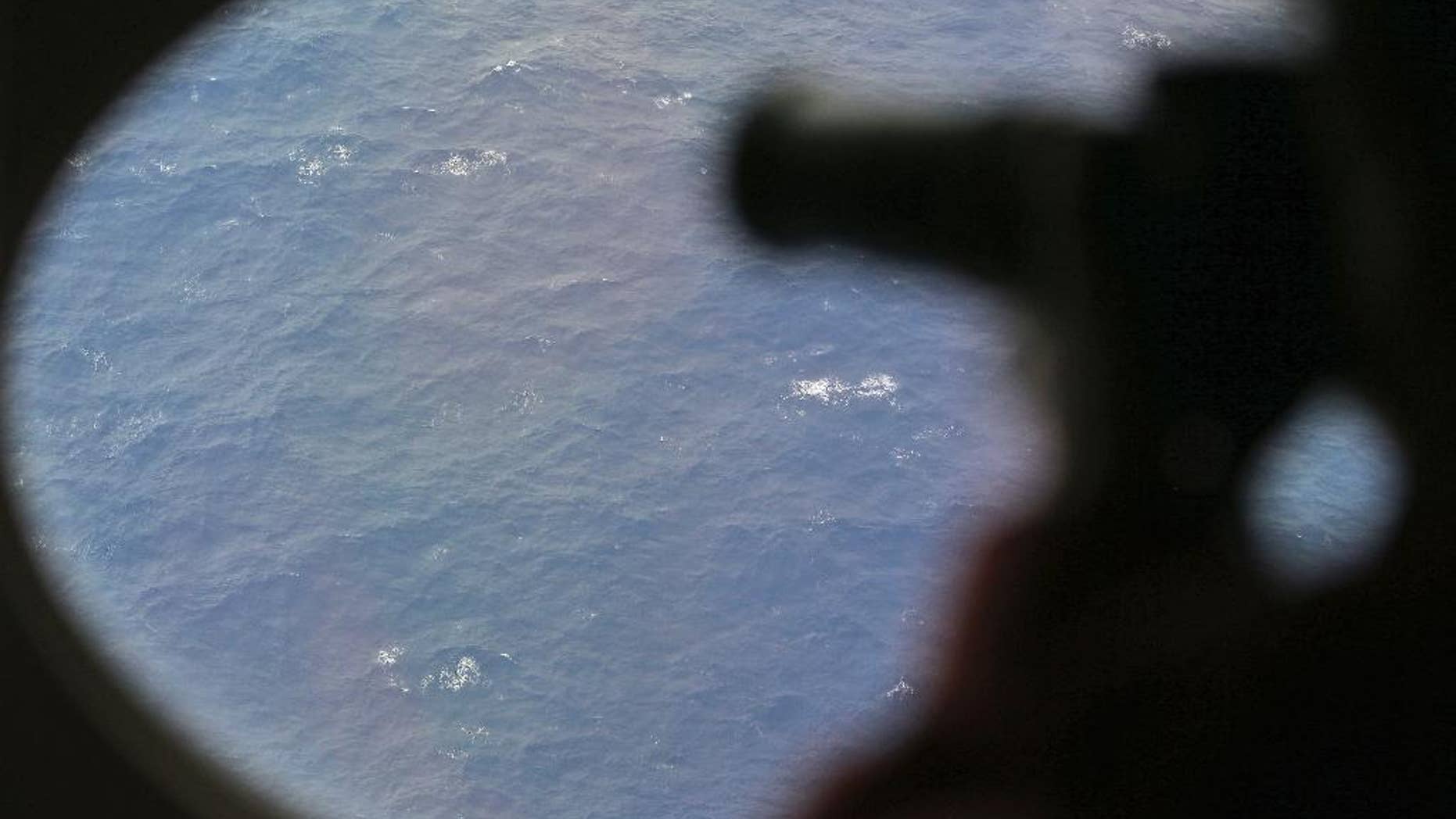 FILE - In this April 1, 2014 file photo, an observer on a Japan Coast Guard Gulfstream aircraft takes photos out of a window while searching for the missing Malaysia Airlines Flight 370 in Southern Indian Ocean. Crews will resume the hunt for missing Malaysia Airlines Flight 370 at the end of the month, and will begin the search in an area farther south than initially planned. Australian Transport Safety Bureau Chief Commissioner Martin Dolan said on Friday, Sept. 19, 2014 that the first of three ships planning to scour the Indian Ocean for the plane should begin searching Sept. 30. (AP Photo/Rob Griffith, Pool, File)