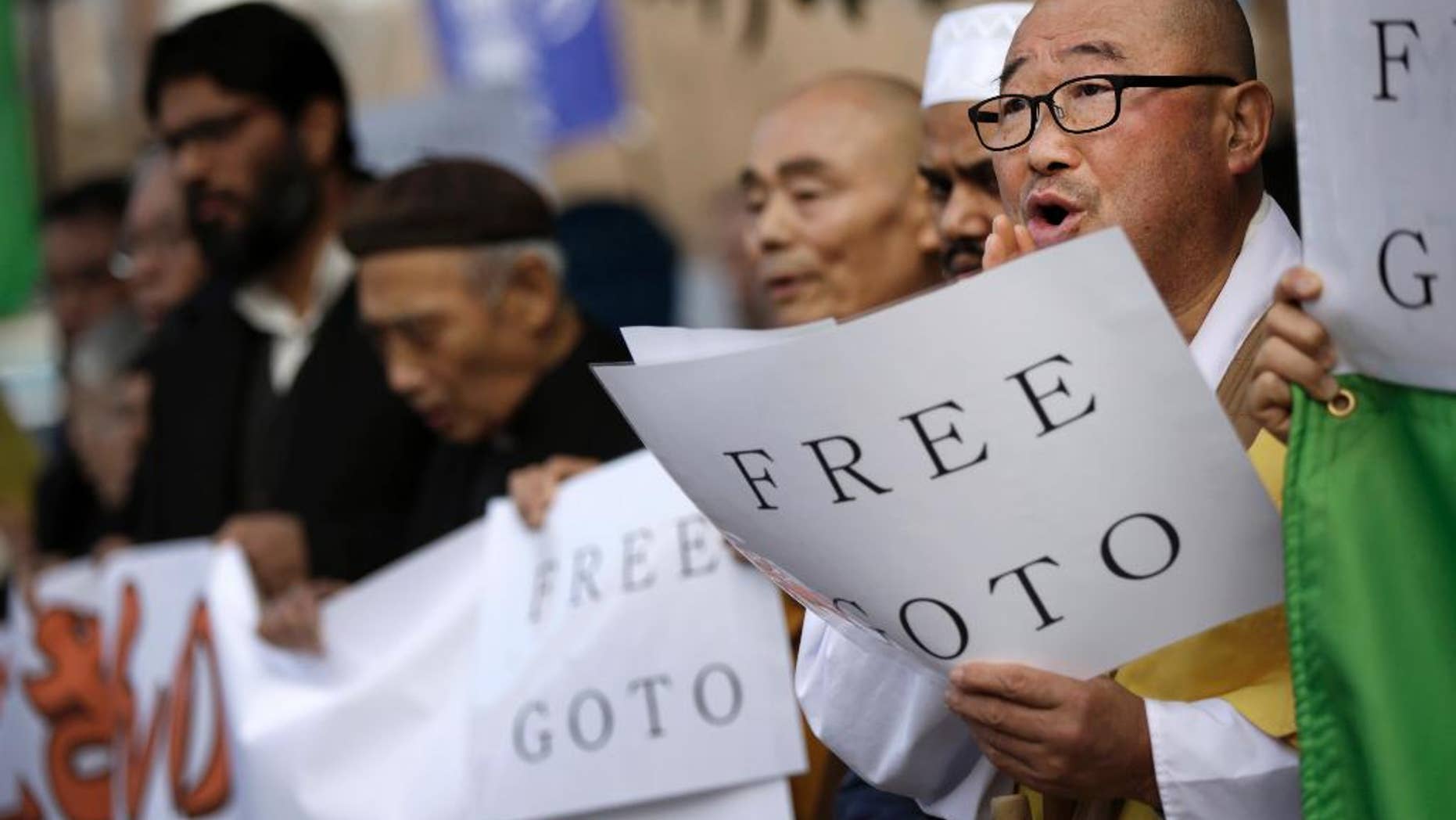 Buddhist monks and other religious group members hold banners and placards to voice their demand about the release of Japanese journalist Kenji Goto taken by the Islamic State, during a rally outside the Prime Minister's official residence in Tokyo, Tuesday, Jan. 27, 2015. A Japanese envoy in Jordan expressed hope that both a Japanese hostage and a Jordanian pilot held by Islamic militants will return home “with a smile on their faces,” as criticisms mounted Tuesday over the government’s handling of the crisis. (AP Photo/Eugene Hoshiko)
