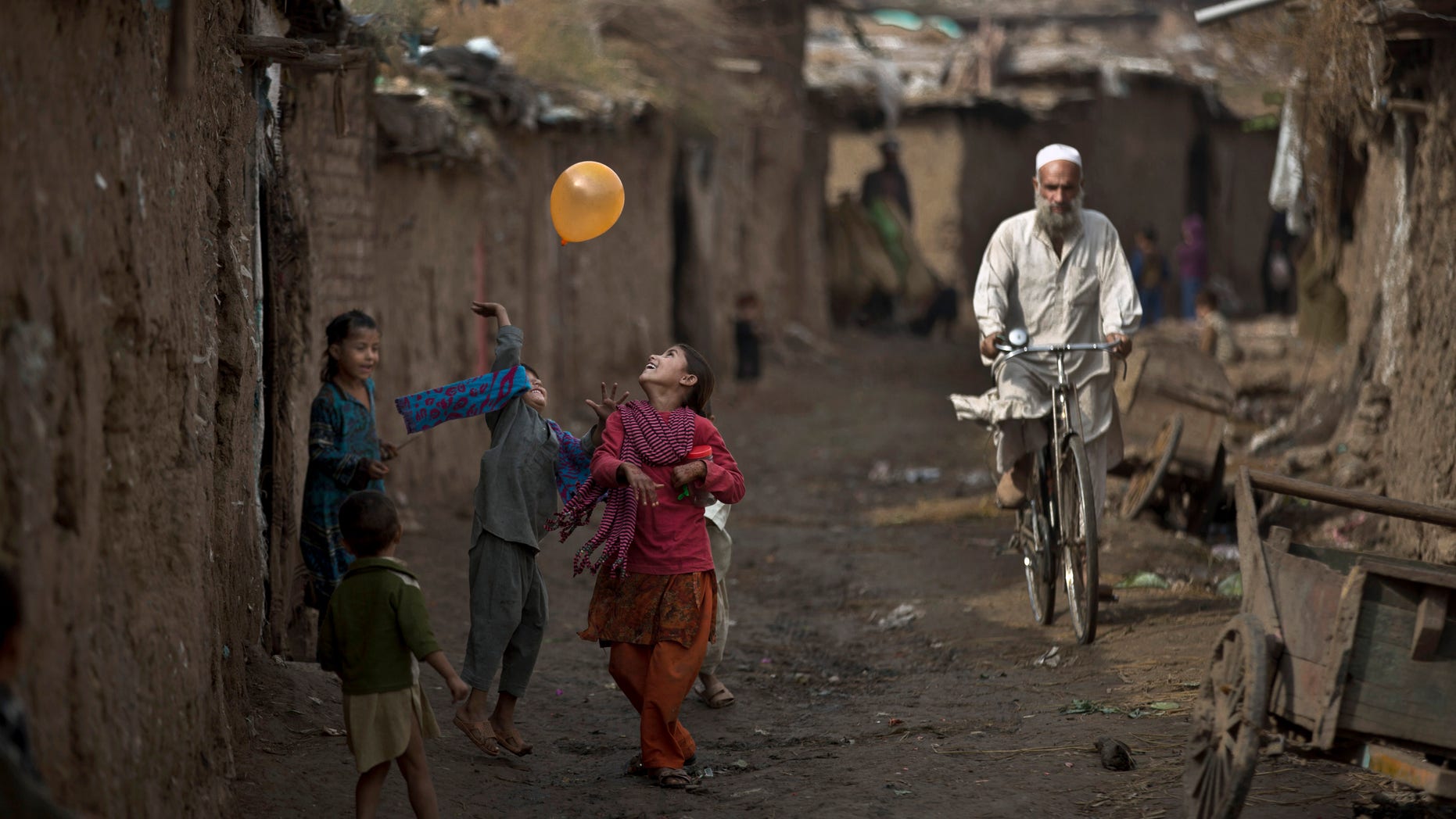 Afghan refugee children play with a balloon in an alley of a poor neighborhood on the outskirts of Islamabad, Pakistan, Thursday, Oct. 31, 2013. Pakistan hosts over 1.6 million registered Afghans, the largest and most protracted refugee population in the world, according to the U.N. refugee agency, thousands of them still live without electricity, running water and other basic services. (AP Photo/Muhammed Muheisen)