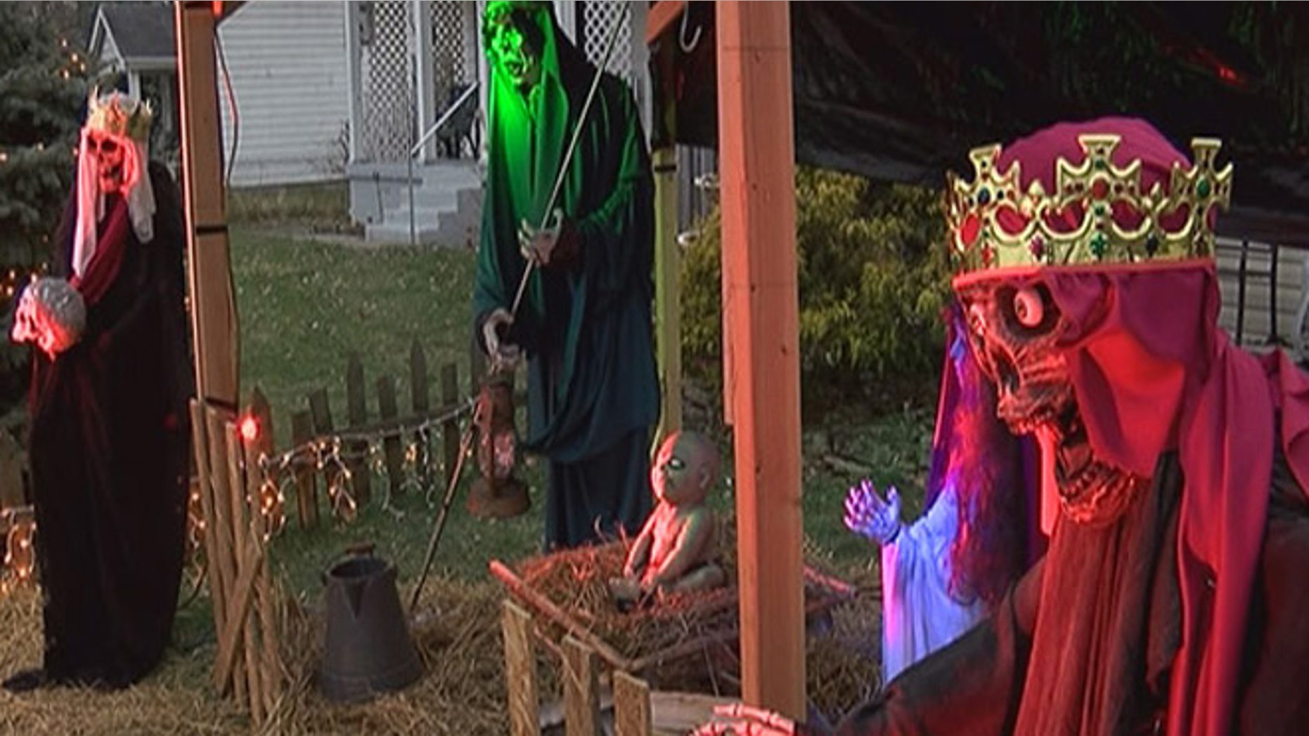 The nativity scene features life-size figures and a zombie baby Jesus, with pale skin and pure white eyes. At night, the figures are illuminated by red and green lights.