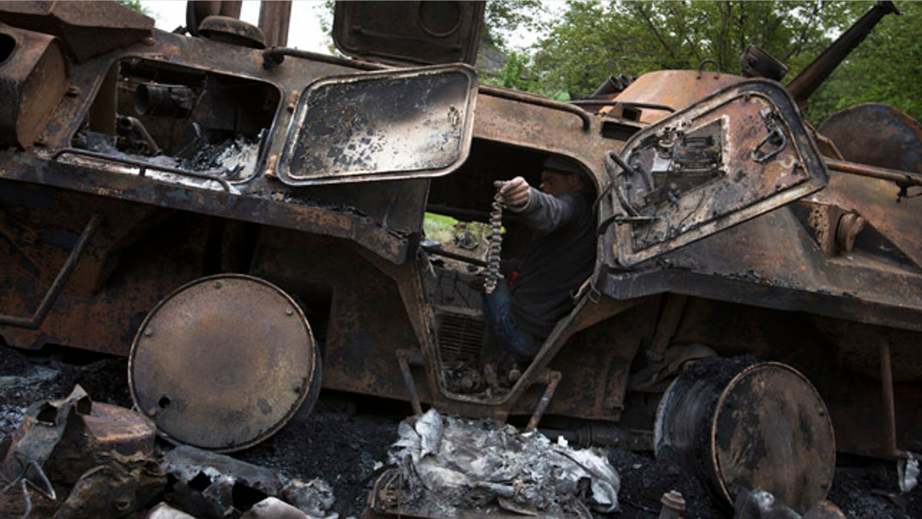 May 14, 2014: A local citizen holds a machine-gun belt as others collect parts of a seized APC that was set alight during a fighting between pro-Russian militants and government troops at Oktyabrskoye village, about 12 miles from Kramatorsk, eastern Ukraine. (AP Photo/Alexander Zemlianichenko)