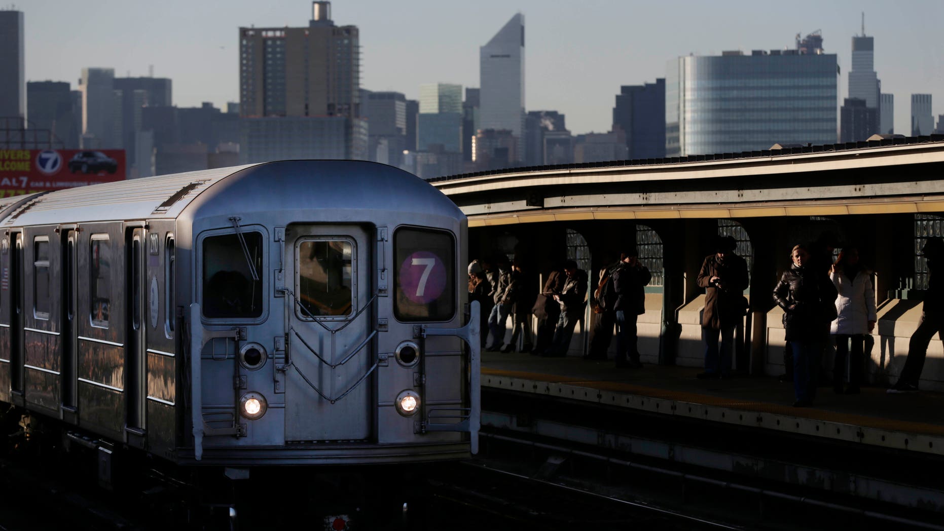 Commuters wait on the platform as a train passes through the 40th St-Lowry St Station, where a man was killed after being pushed onto the subway tracks, in the Queens section of New York, Friday, Dec. 28, 2012. Police are searching for a woman suspected of pushing the man and released surveillance video Friday of her running away from the station. (AP Photo/Seth Wenig)