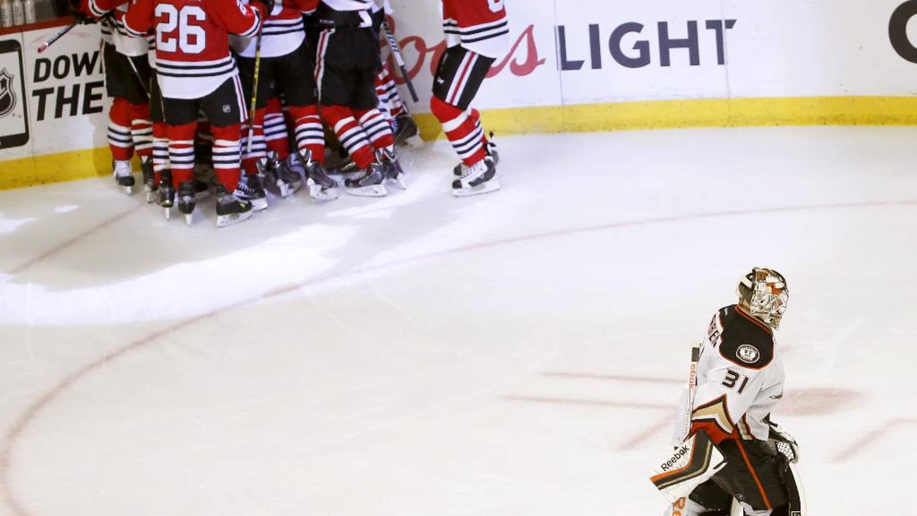 Anaheim Ducks goalie Frederik Andersen (31) and teammate Cam Fowler (4) skate off the ice as the Chicago Blackhawks celebrate their 5-4 win during the second overtime in Game 4 of the Western Conference finals of the NHL hockey Stanley Cup playoffs, Saturday, May 23, 2015, in Chicago. (AP Photo/Charles Rex Arbogast)