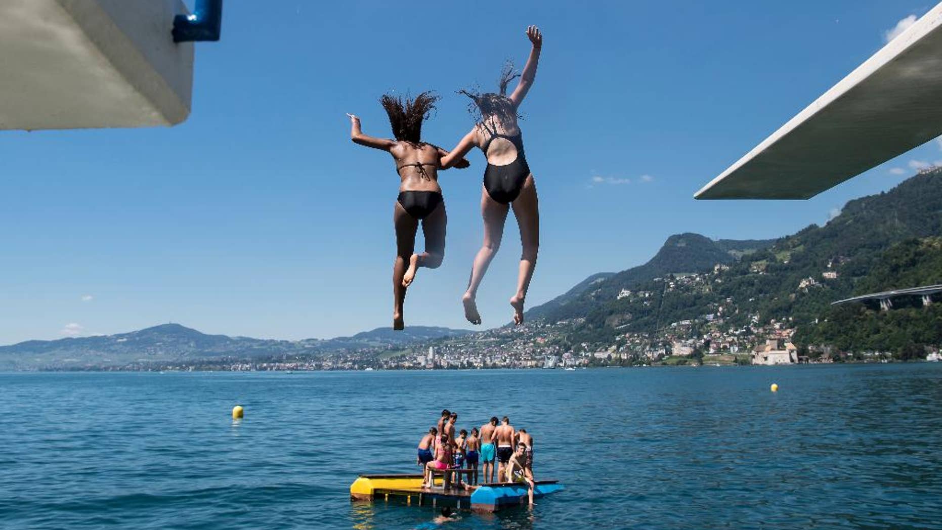 FILE - In this July 9, 2016 file photo, girls jump from a diving platform into the Geneva Lake and enjoy sunny and warm weather, in Villeneuve, Switzerland. After nearly 90 years, women can legally swim topless in Geneva’s lake and Rhone River without running the risk of a fine. Geneva’s regional council has voted to modify a 1929 ordinance that banned women from swimming topless in the city’s main natural waterways, though the change doesn’t apply to public swimming pools or swimming totally naked. Nicolas Bolle, an official with Geneva’s security department, on Thursday, April 6, 2017 confirmed the council’s action a day earlier. (Jean-Christophe Bott/Keystone via AP,file)
