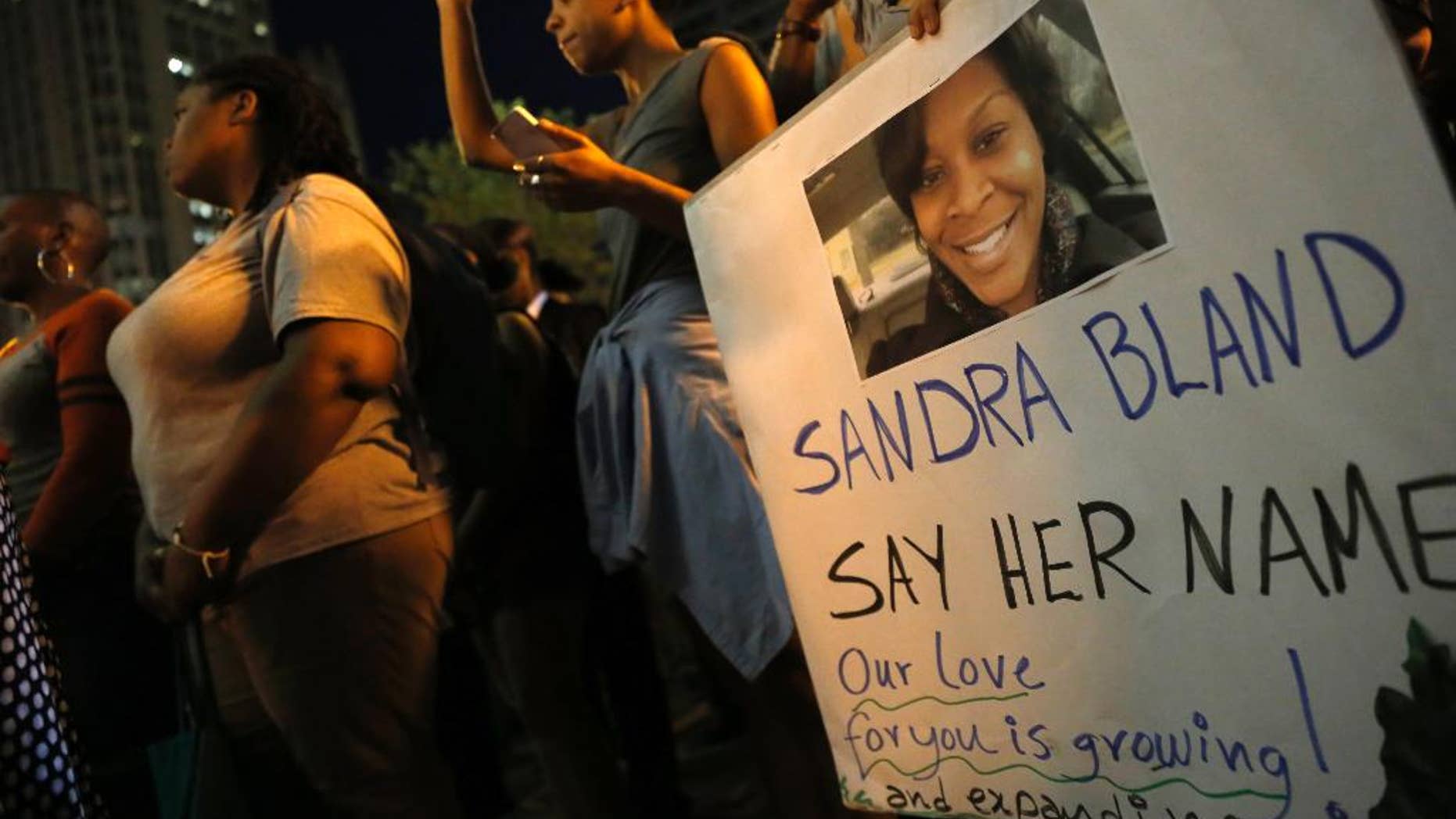 A demonstrator holds a Sandra Bland sign during a vigil, Tuesday evening, July 28, 2015, near the DuSable Bridge on Michigan Ave. in Chicago. Bland died in a Texas county jail after the traffic stop for failing to use a turn signal escalated into a physical confrontation. Authorities have said Bland hanged herself, a finding her family disputes. The death has garnered national attention amid increased scrutiny of police treatment of blacks in the wake of several high-profile police-involved deaths. (AP Photo/Christian K. Lee)