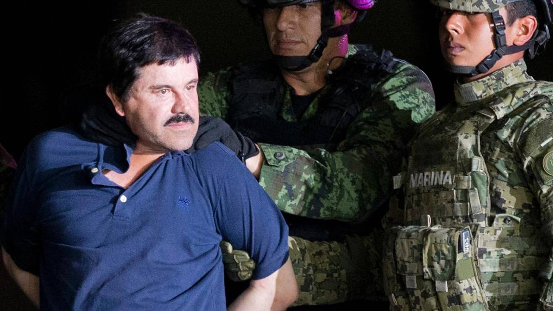 FILE - In this Jan. 8, 2016 file photo, a handcuffed Joaquin "El Chapo" Guzman is made to face the press as he is escorted to a helicopter by Mexican soldiers and marines at a federal hangar in Mexico City. Guzman is scheduled to appear in person in a federal court in New York. A judge initially ruled that Guzman would appear in court by video on Friday, Feb. 3, rather than have marshals escort him to and from a high-security Manhattan jail cell. The order was changed after his lawyers asked the judge to reconsider. (AP Photo/Eduardo Verdugo, File)