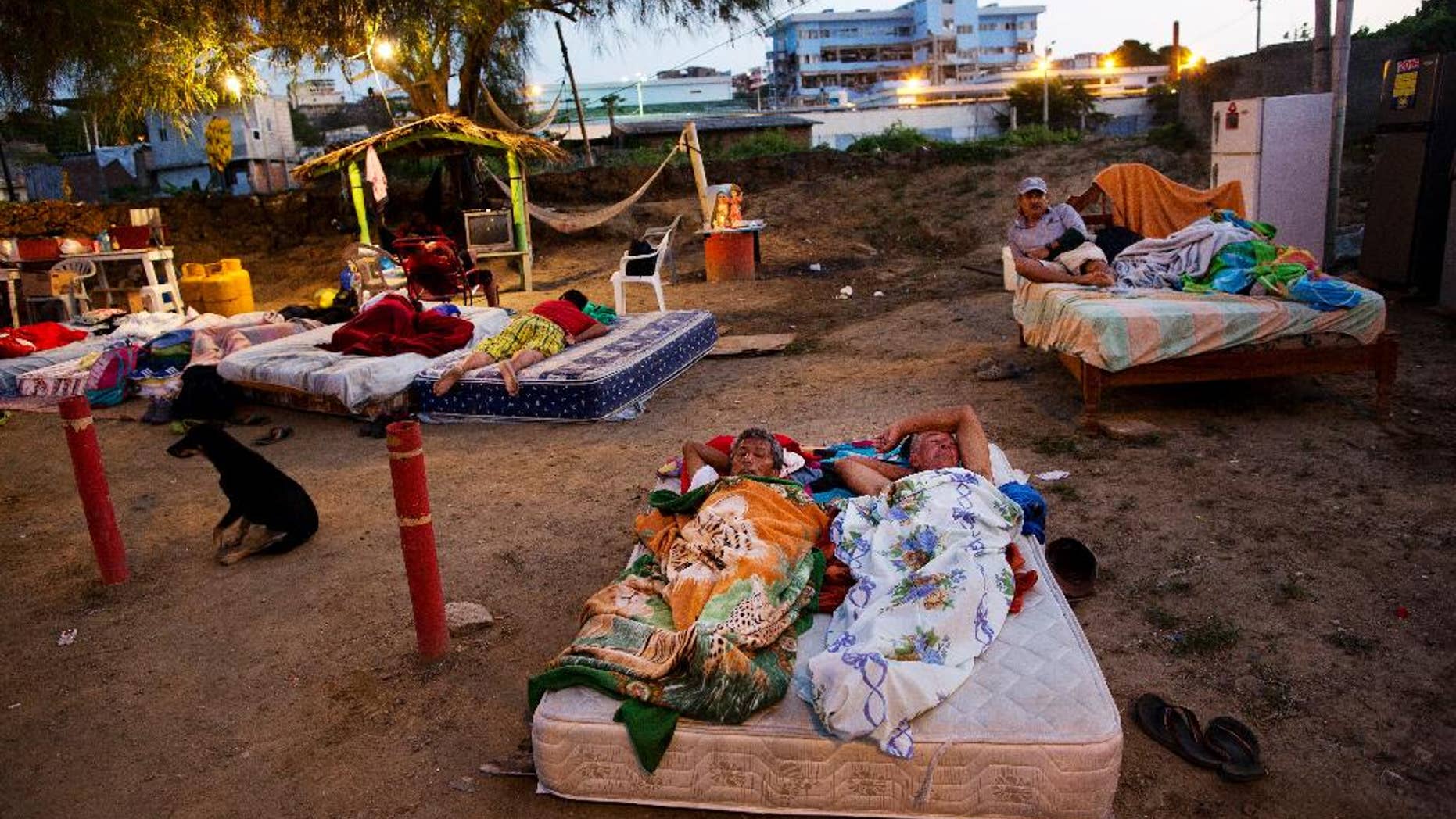 In this Wednesday, April 20, 2016 photo, neighbors Carlos Bardales, left, and Cesar Filay, share a mattress as they sleep outside their collapsed homes damaged by a 7.8-magnitude earthquake, in Manta, Ecuador. Hundreds of aftershocks have rattled the country since last Saturday night's quake and Ecuadoreans are still sleeping outside and struggling to find food and water. (AP Photo/Rodrigo Abd)