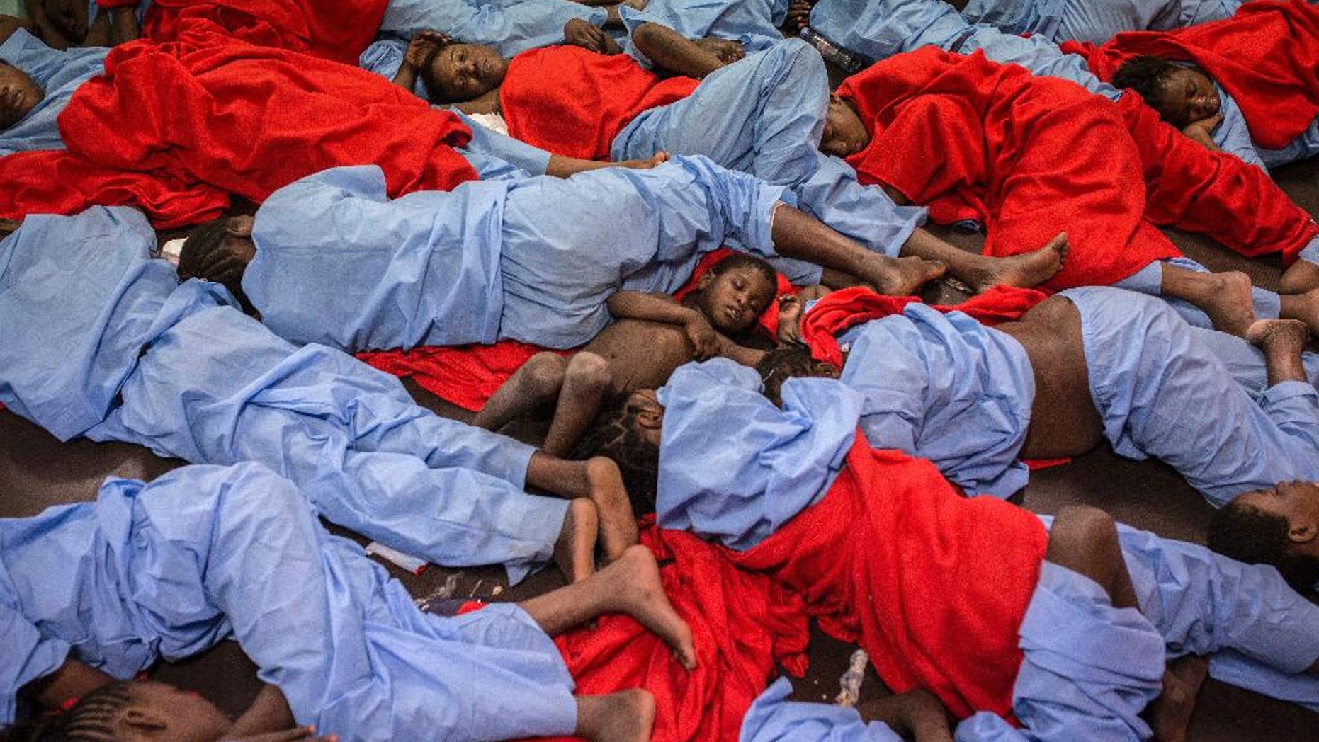 In this Friday Jan. 13, 2017 photo, Idris 3, from Mali, center, sleeps next to his mother Aicha Keita, right, on the deck of the Golfo Azzurro vessel after being rescued from the Mediterranean sea, about 20 miles north of Ra's Tajura, Libya. Spain's maritime rescue service says the bodies of seven African migrants have been found dead along the Strait of Gibraltar since Friday. (AP Photo/Olmo Calvo)