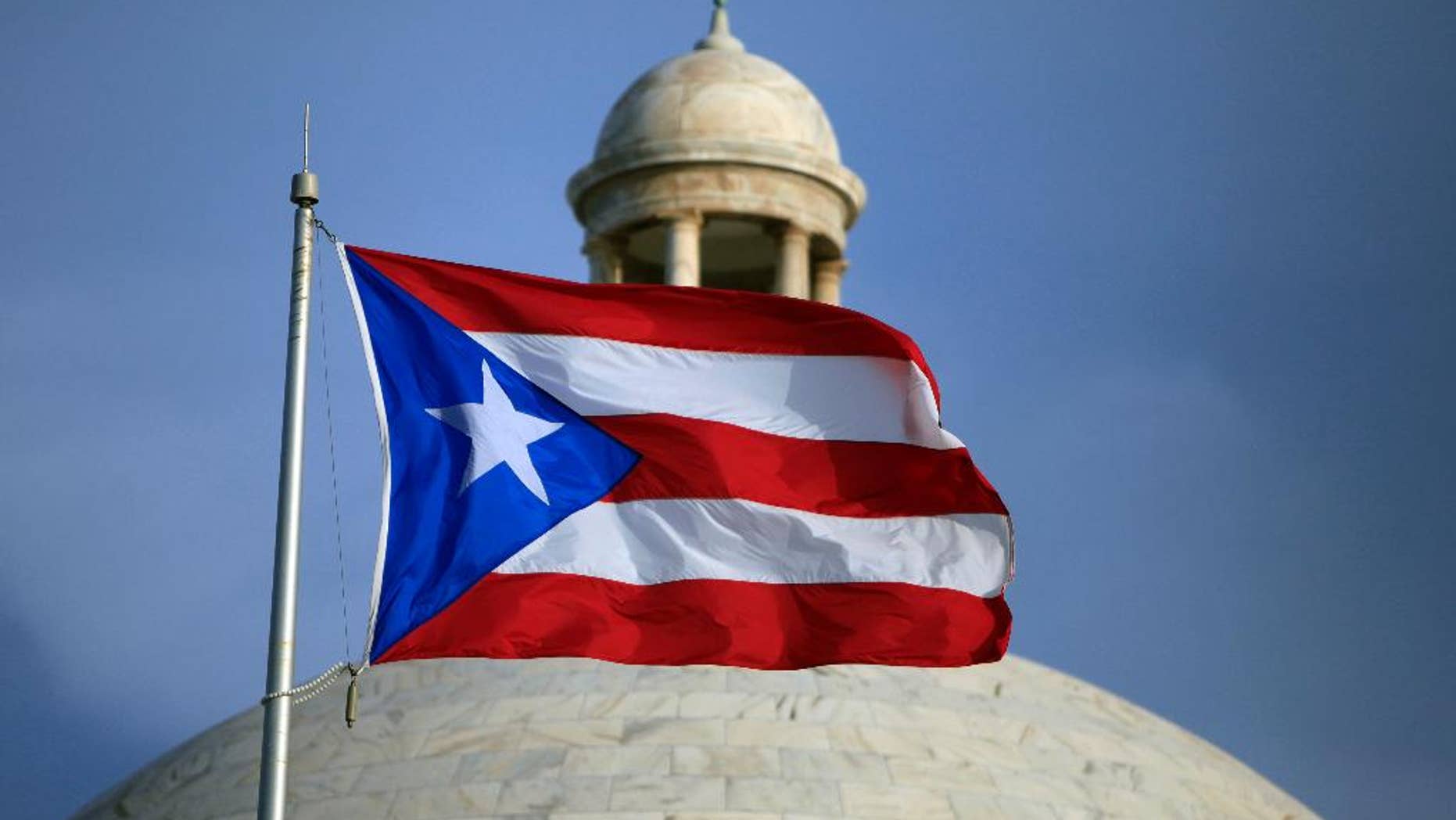 FILE - In this Wednesday, July 29, file 2015 photo, the Puerto Rican flag flies in front of Puerto Rico’s Capitol as in San Juan, Puerto Rico. On Monday, April 11, 2016, Puerto Rico released a new proposal to restructure part of its $70 billion debt to buy time to implement a fiscal growth plan as multimillion-dollar payments loom for a U.S. territory facing dwindling cash reserves. (AP Photo/Ricardo Arduengo, File)