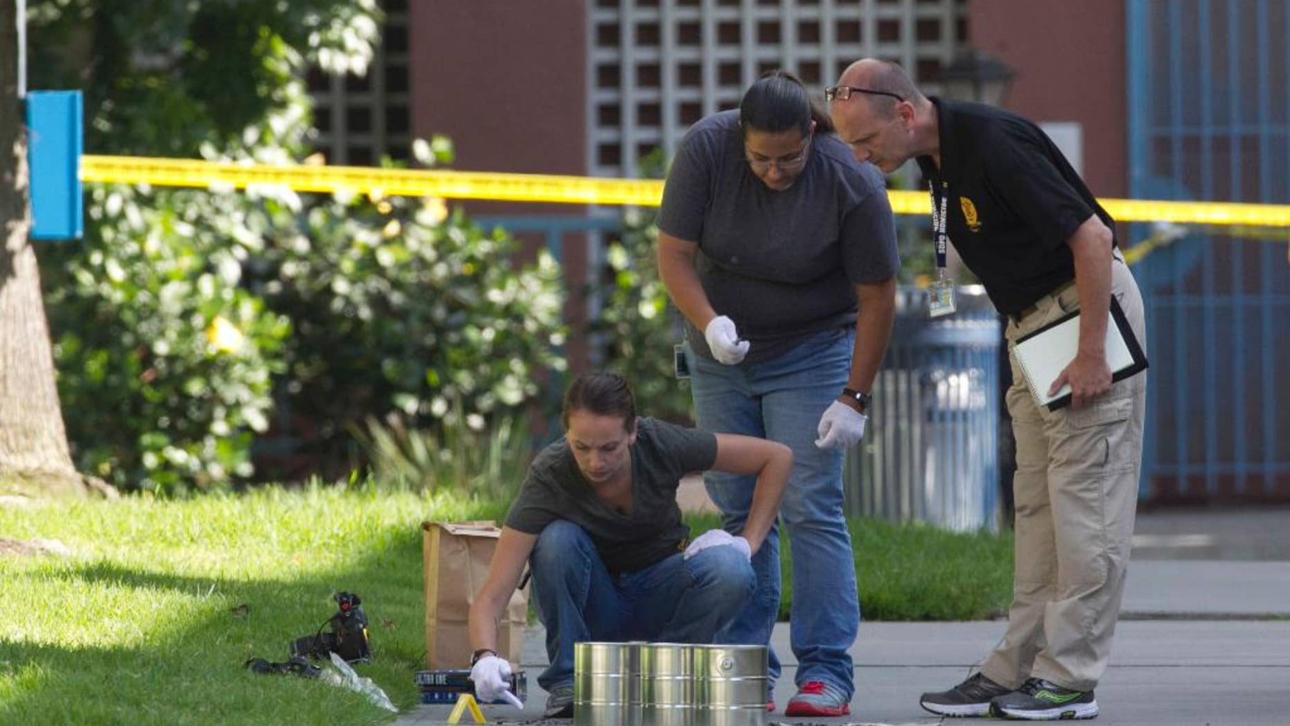 San Diego's Metro Arson Strike Team and SDPD homicide team on July 6 gathering evidence from the sidewalk and grassy area where a homeless person was attacked.