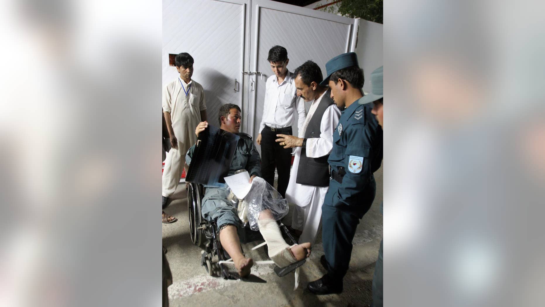 An Afghan injured policeman receives treatment as he sits in a wheelchair, at Lashkar Gah Hospital, after a suicide attack in the city of Lashkar Gah, capital of Helmand Province southern of Kabul, Afghanistan, Sunday, April, 19, 2015. Insurgents armed with guns and explosives entered a police station in Afghanistan's southern city of Lashkar Gah on Sunday after a suicide bomber detonated explosives at the gate of the compound allowing the others to gain entry, a senior policeman said. (AP Photo/Abdul Khaliq)