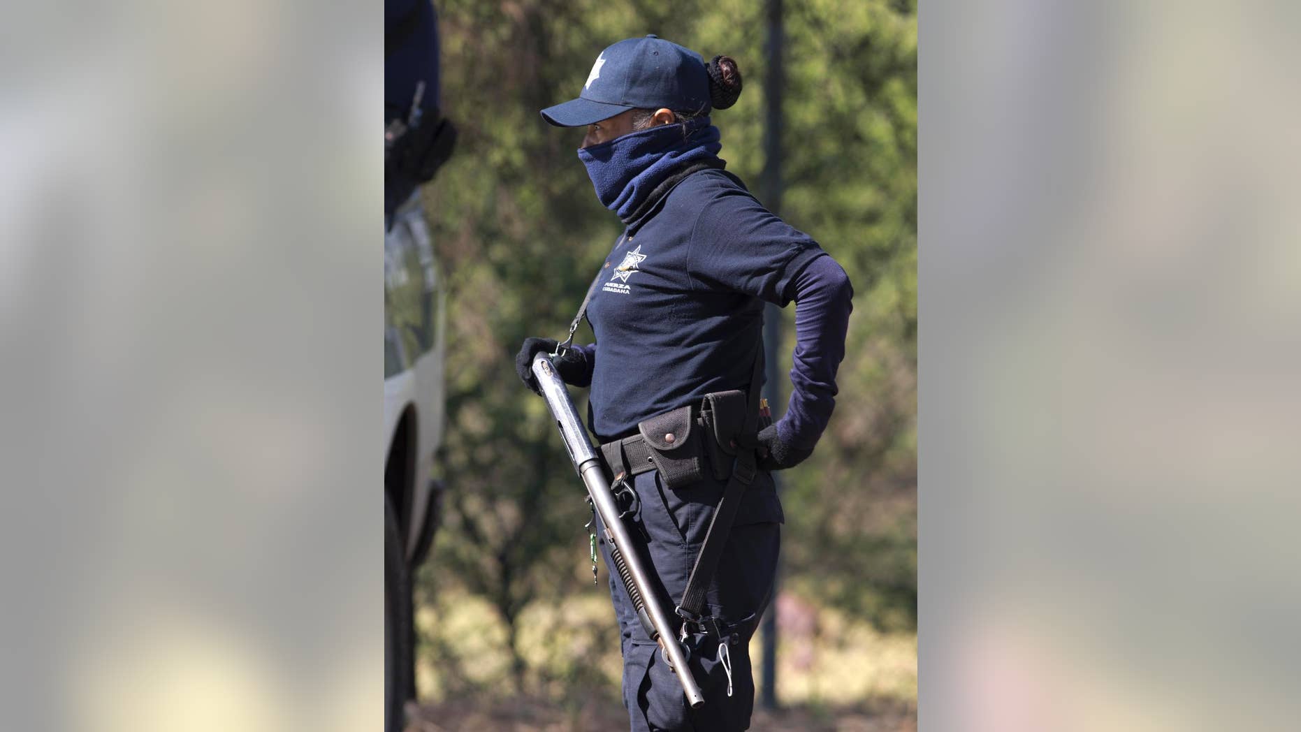 A masked police officer stands guard just inside the entrance of Rancho del Sol, a ranch that was the site of clashes between Mexican authorities and a drug cartel, in the municipality of Ecuandureo, Mexico, Saturday, May 23, 2015. The clash was the deadliest confrontation in recent memory, with 42 suspected gang gunmen and one Federal Police officer killed during a three-hour firefight on Friday at this remote western ranch. (AP Photo/Eduardo Verdugo)