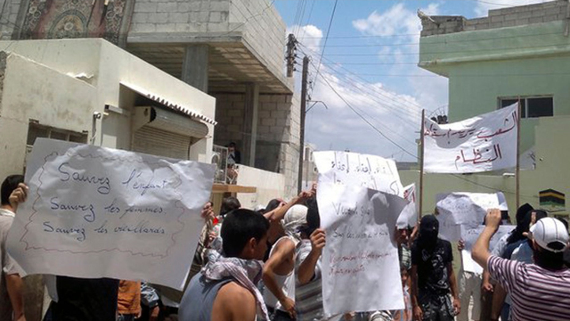 June 30: In this citizen journalism image made on a mobile phone and provided by Shaam News Network, anti-Syrian President Bashar Assad protesters hold banners during a demonstration against the Syrian regime in the coastal city of Banias, Syria.