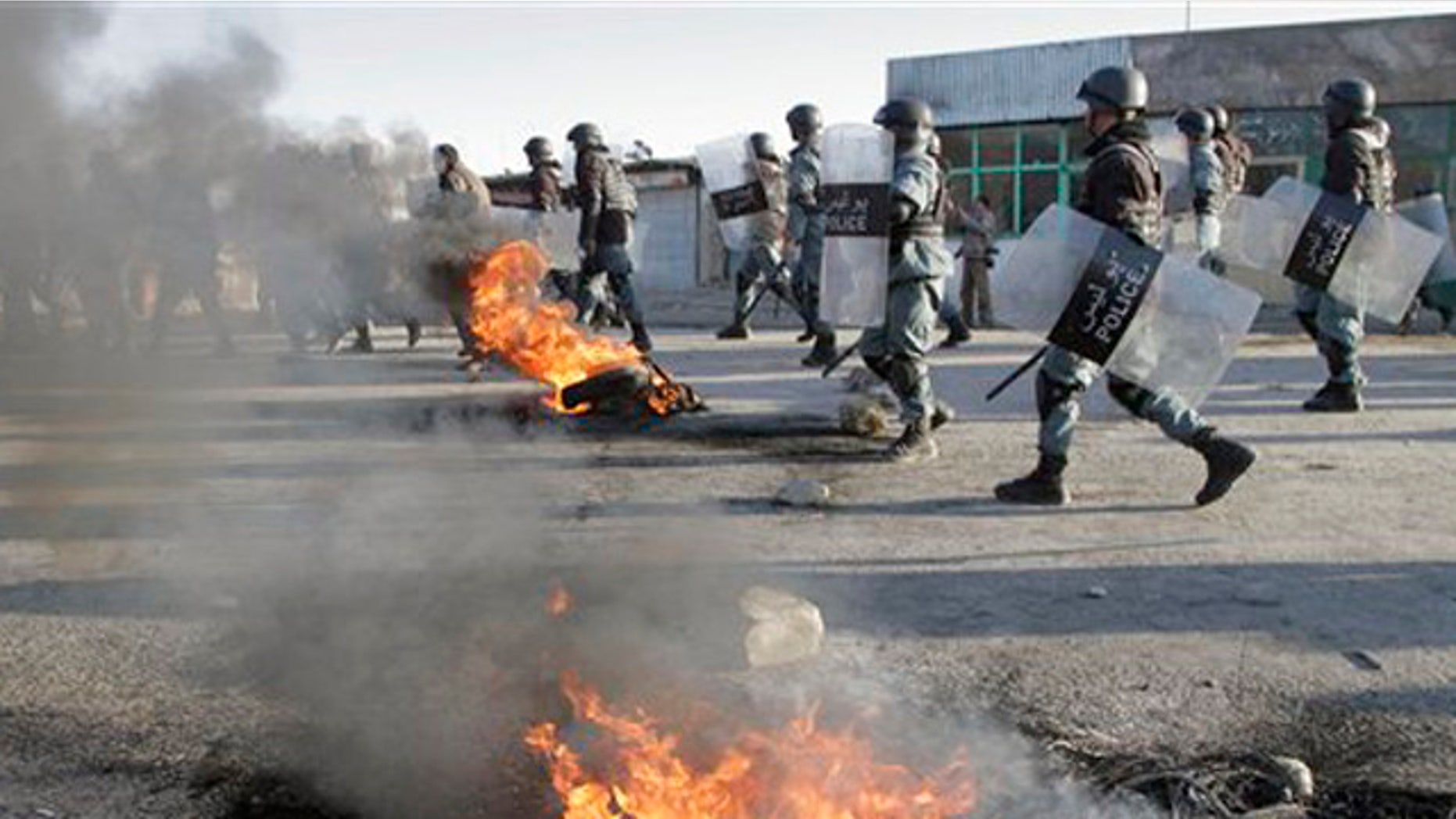 Feb. 24, 2012: Afghan policemen walk past burning tires during an anti-U.S. demonstration in Kabul, Afghanistan.
