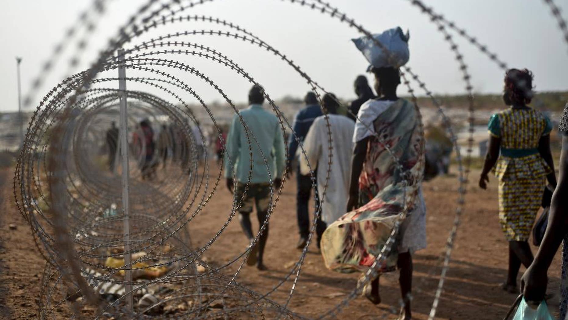 FILE - In this Tuesday Jan. 19, 2016 file photo, displaced people walk next to a razor wire fence at the United Nations base in the capital Juba, South Sudan. A U.N. team of human rights investigators said Friday Dec. 2, 2016, that rape in South Sudan is one of the tools being used for ethnic cleansing, adding that sexual violence in the East African nation has reached epic proportions. (AP Photo/Jason Patinkin, File)