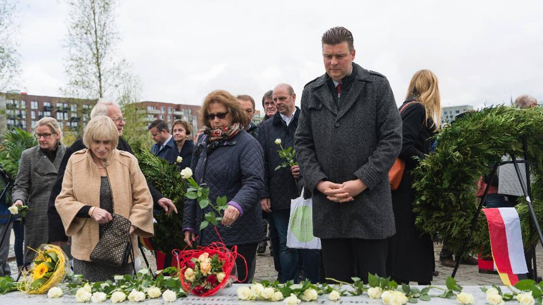 People place white roses on a memorial that was unveiled in the German port city of Hamburg to Jewish and Roma residents who were killed during the Nazi Holocaust, Wednesday, May 10, 2017. (Christophe Gateau/dpa via AP)