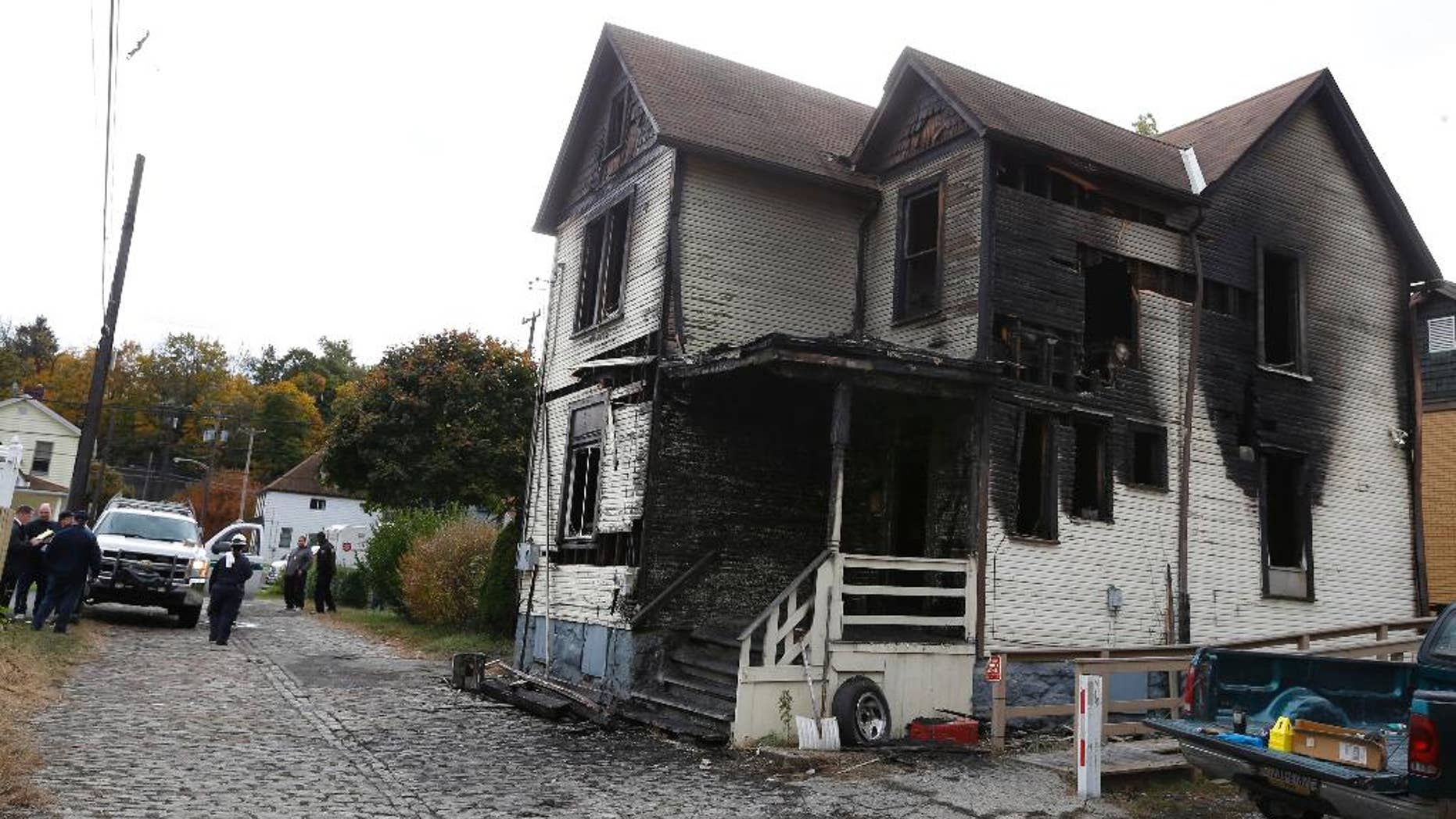 FILE - In this Saturday, Oct. 18, 2014 file photo, emergency workers gather in front of a burned house in McKeesport, Pa. Authorities allege that Ryan Williams, 24, set the Pittsburgh-area fire which killed six people, four of them children, because he wanted to get revenge on someone in the house. Williams, of McKeesport, was charged in Allegheny County on Friday, Jan, 16, 2015 with six counts of criminal homicide, arson and burglary in the fire. The blaze killed 55-year-old Ronald Egenlauf Sr., his 27-year-old daughter-in-law Hope Jordan, and her four children, ages 2 through 7. (AP Photo/Keith Srakocic)