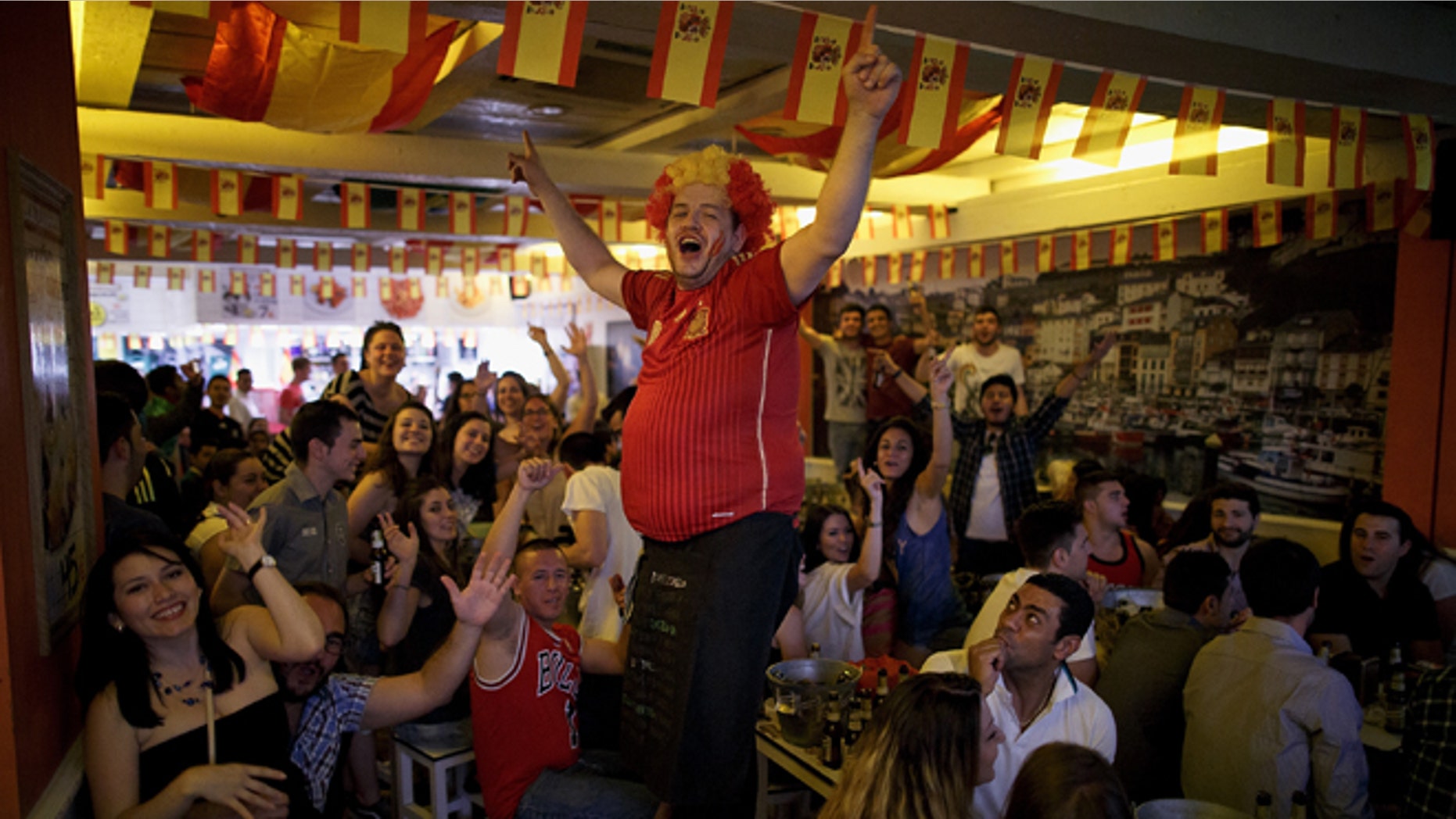 MADRID, SPAIN - JUNE 13: A waiter cheers up Spanish soccer fans watching their team playing against the Netherlands in a Madrid tavern during Spain's first FIFA World Cup match on June 13, 2014 in Madrid, Spain. Spain are the current Champions after they won 2010 World Cup final against Holland, but today they lost the match 5-1. (Photo by Pablo Blazquez Dominguez/Getty Images)