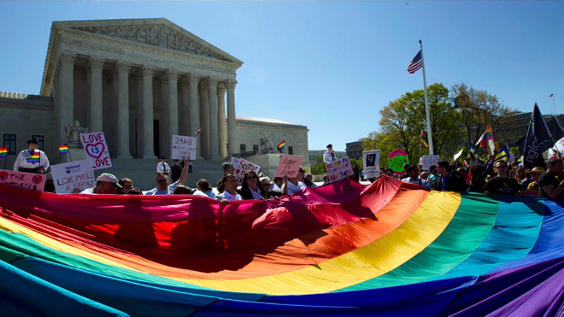 FILE - In this April 28, 2015, file photo, demonstrators stand in front of a rainbow flag of the Supreme Court in Washington, as the court was set to hear historic arguments in cases that could make same-sex marriage the law of the land. Gay and lesbian couples could face legal chaos if the Supreme Court rules against same-sex marriage in the next few weeks. Same-sex weddings could come to a halt in many states, depending on a confusing mix of lower-court decisions and the sometimes-contradictory views of state and local officials. Among the 36 states in which same-sex couples can now marry are 20 in which federal judges invoked the Constitution to strike down marriage bans. (AP Photo/Jose Luis Magana, File)