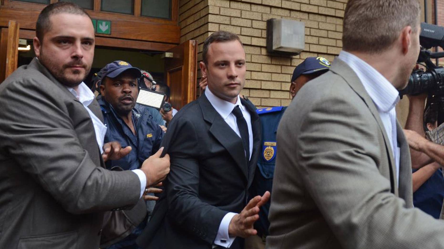 Oscar Pistorius, center, is escorted out of the high court after the first day of his trial in Pretoria, South Africa, Monday, March 3, 2014. Pistorius is charged with murder with premeditation in the shooting death of girlfriend Reeva Steenkamp in the pre-dawn hours of Valentine's Day 2013. (AP Photo)