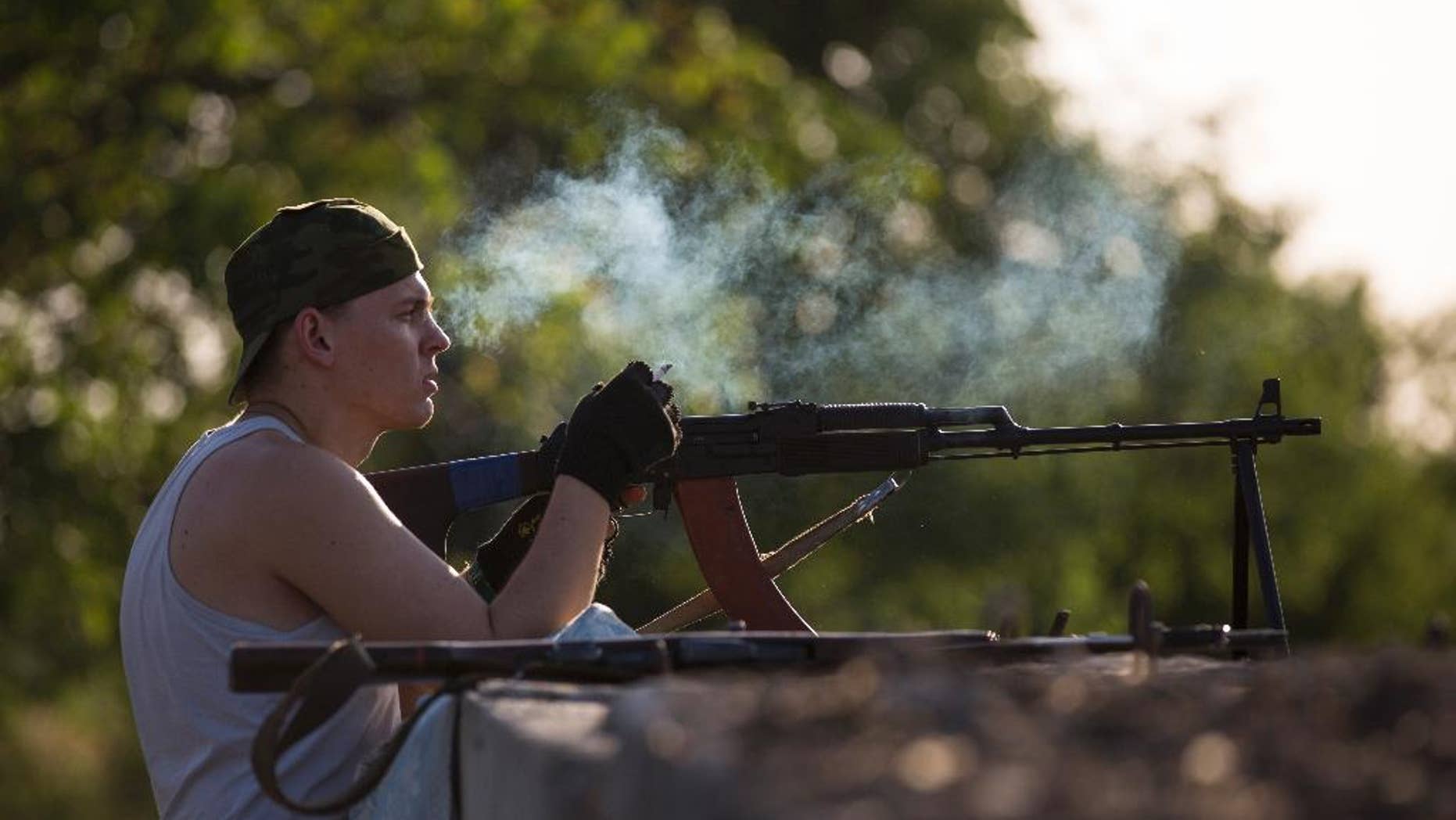 A pro-Russian militant smokes a cigarette as he takes his position preparing to fight against Ukrainian government troops at a checkpoint blocking the major highway which links Kharkiv, outside Slovyansk, eastern Ukraine, Friday, May 16, 2014. Outside the strategic city of Slovyansk, which has been the key stronghold of the pro-Russian insurgents for more than a month now, the armed separatists installed a new check-point on the eastern approaches of the city blocking the major highway which links Kharkiv, the capital of the neighboring region, and the Russian city of Rostov-on-Don across the border. (AP Photo/Alexander Zemlianichenko)