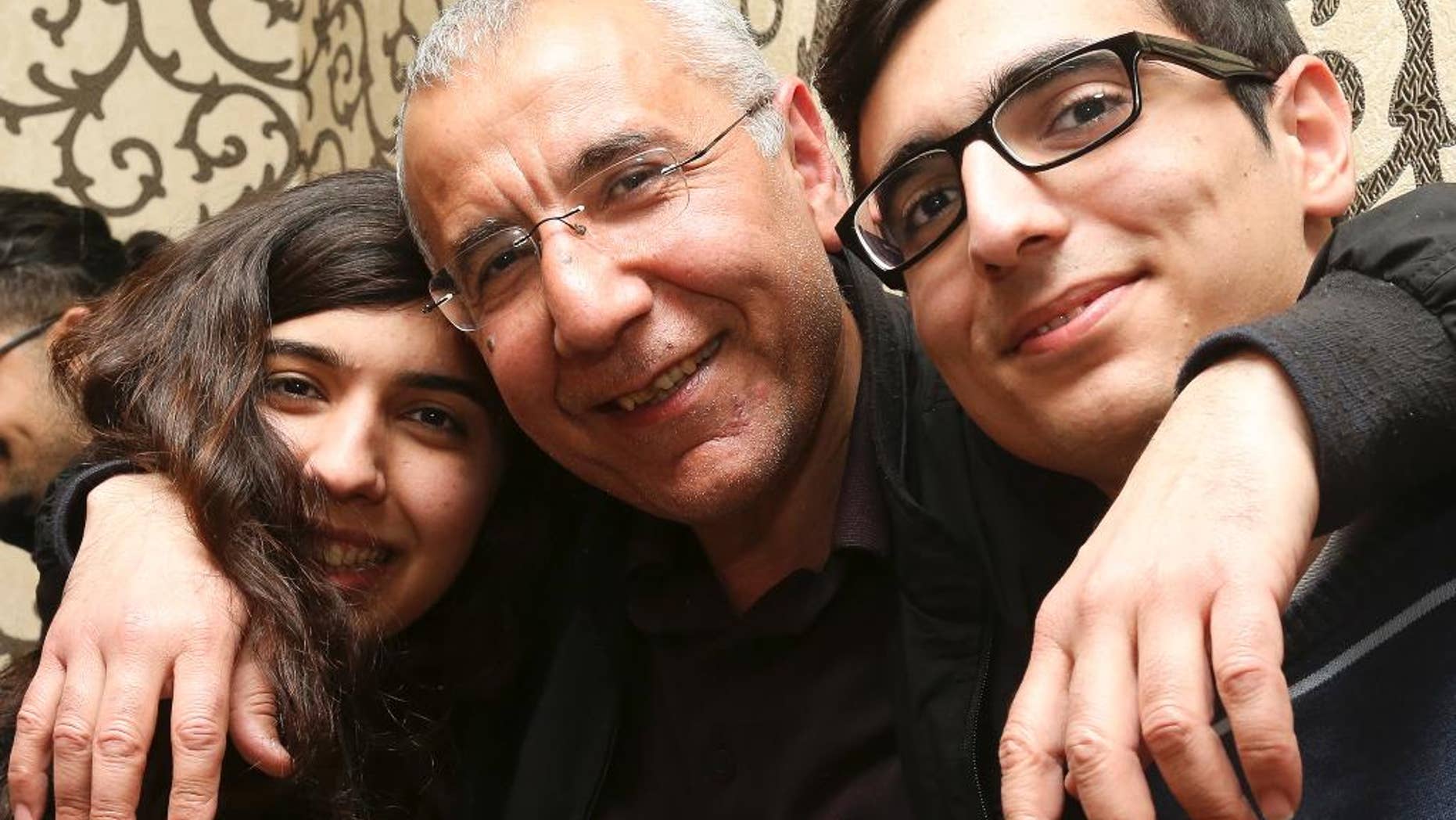 Human rights activist Intigam Aliyev, center, poses for a photo with his son and daughter upon his release at home in Baku, Azerbaijan, Monday, March 28, 2016. A court in Azerbaijan has ordered the release of a human rights activist who spent the last two years in jail. Aliyev was convicted last year of economic crimes that critics have dismissed as retaliation for his work. (AP Photo/Aziz Karimov)