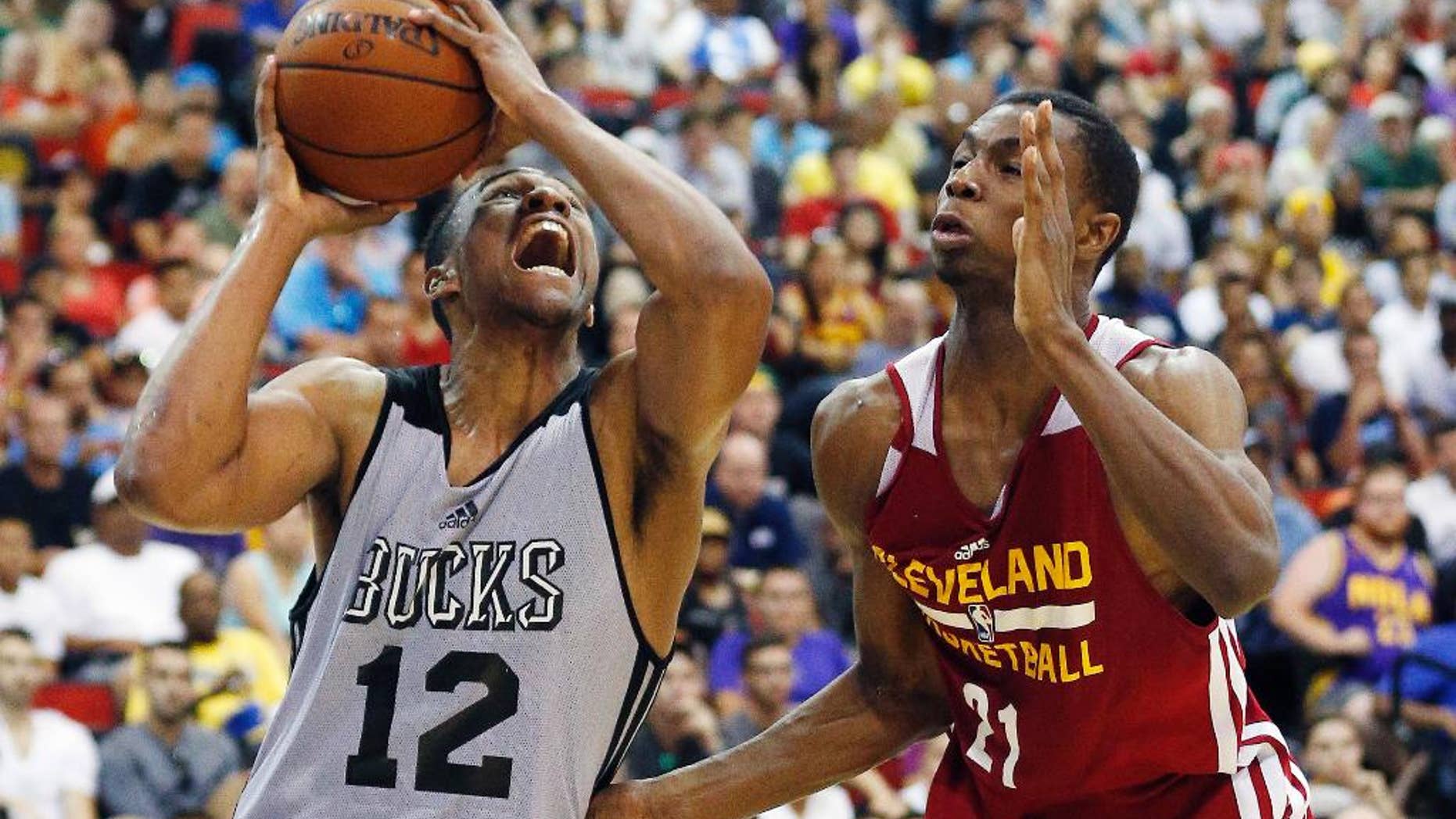 Jabari Parker (12) of the Milwaukee Bucks drives by Andrew Wiggins of the Cleveland Cavaliers in an NBA summer league basketball Friday, July 11, 2014, in Las Vegas. (AP Photo/John Locher)