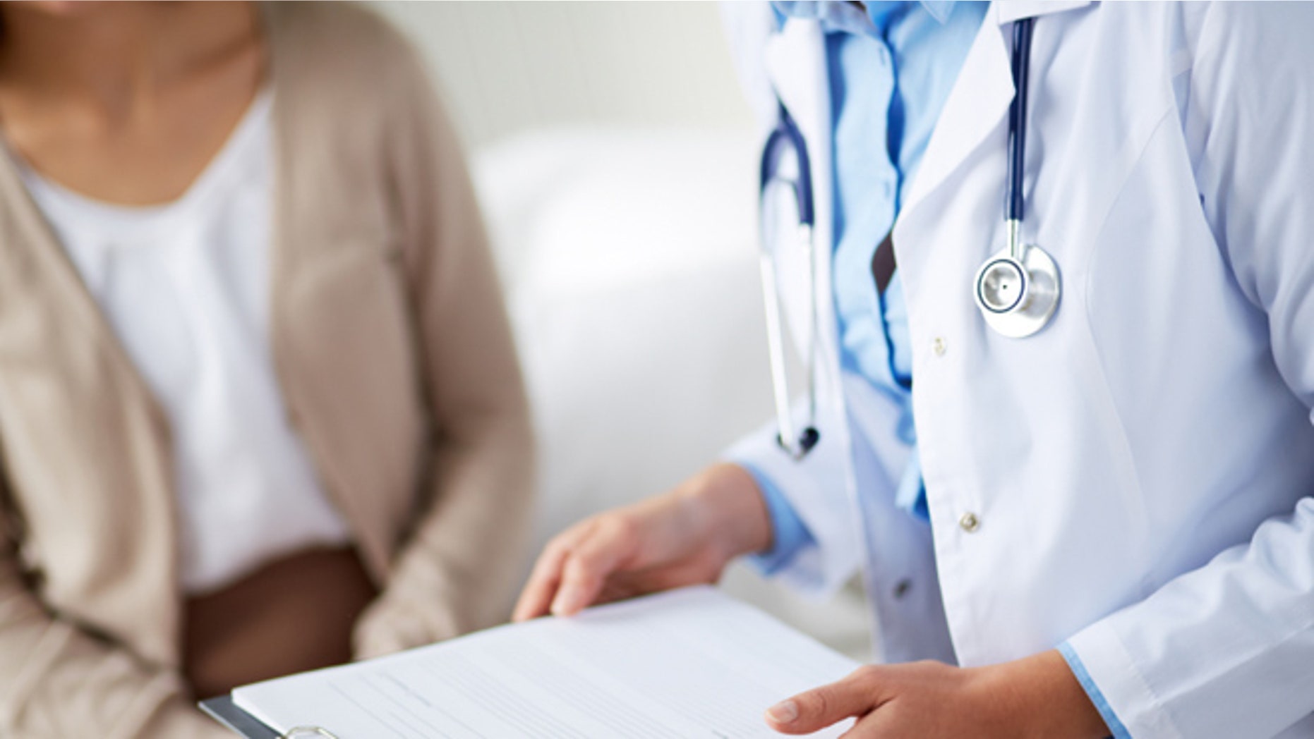 Female doctor holding application form while consulting patient