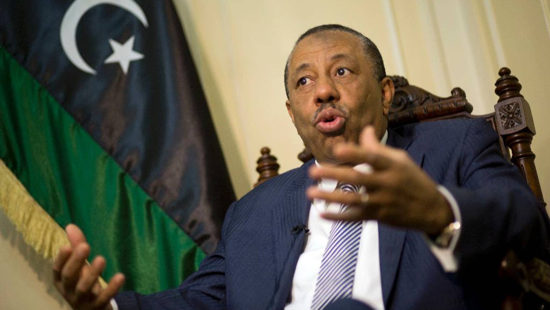 Libyan Prime Minister Abdullah al-Thinni, speaks during an interview with the Associated Press at the Libyan embassy in Cairo, Egypt, Tuesday, July 5, 2016. Al-Thinni of the interim government based in the eastern region, told The Associated Press that the UN-brokered deal has reached a deadlock. The deal must be amended, he said. Libyan flag seen at background.(AP Photo/Amr Nabil)