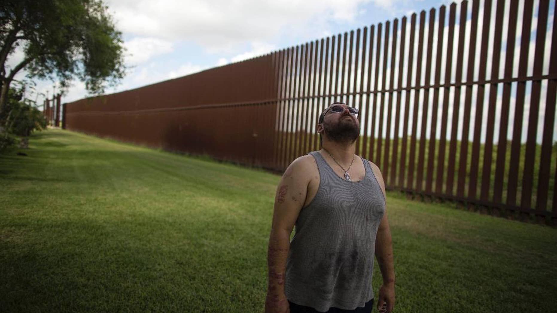 FILE - In this March 22, 2017, file photo, Antonio Reyes of Brownsville, Texas, stands by the U.S.-Mexico border fence near his home. (AP Photo/Rodrigo Abd, File)
