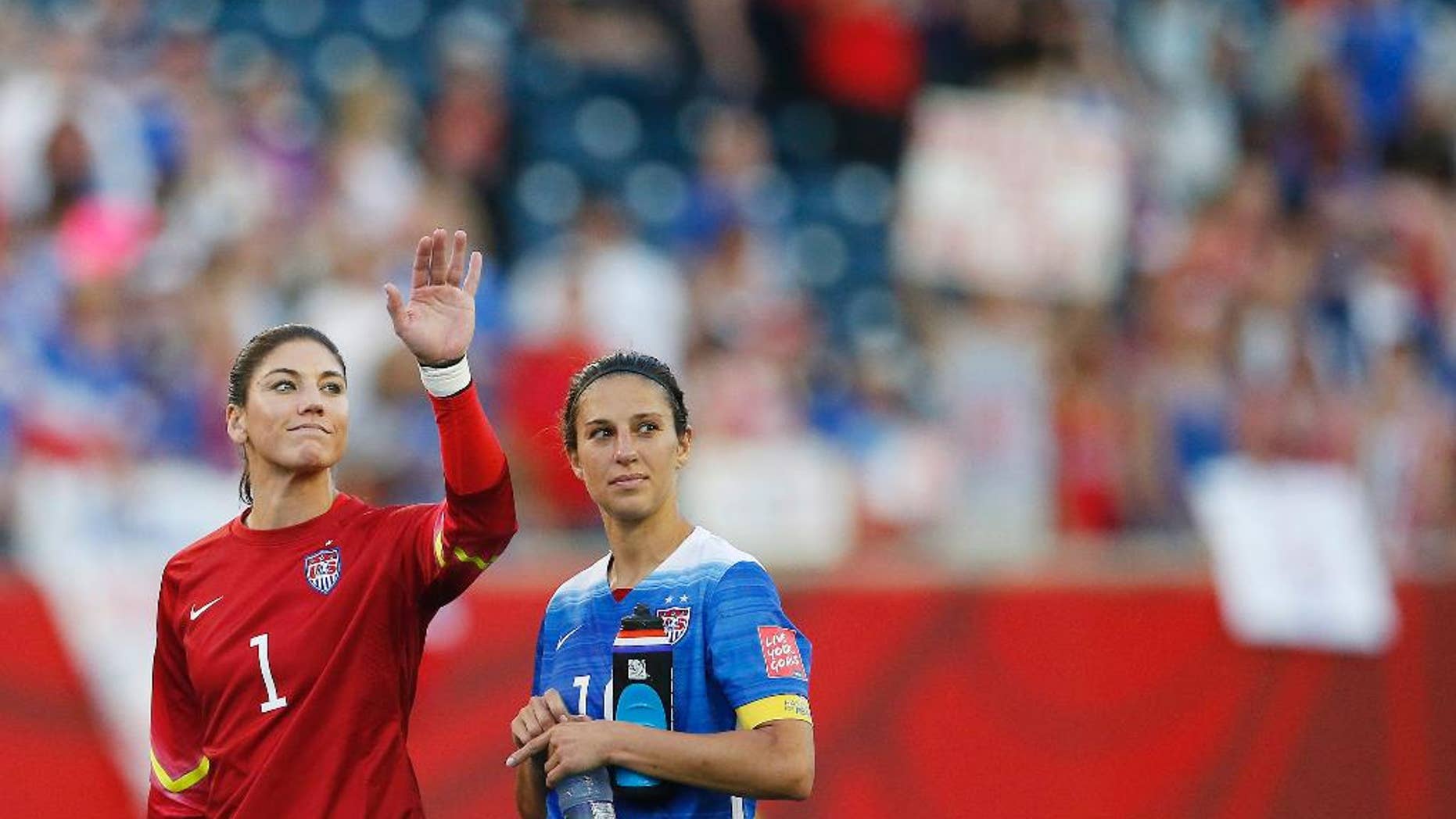 United States goalkeeper Hope Solo (1) waves to the crowd next to teammate Carli Lloyd (10) after their draw against Sweden in FIFA Women's World Cup soccer game action in Winnipeg, Manitoba, Canada, Friday, June 12, 2015. (John Woods/The Canadian Press via AP) MANDATORY CREDIT
