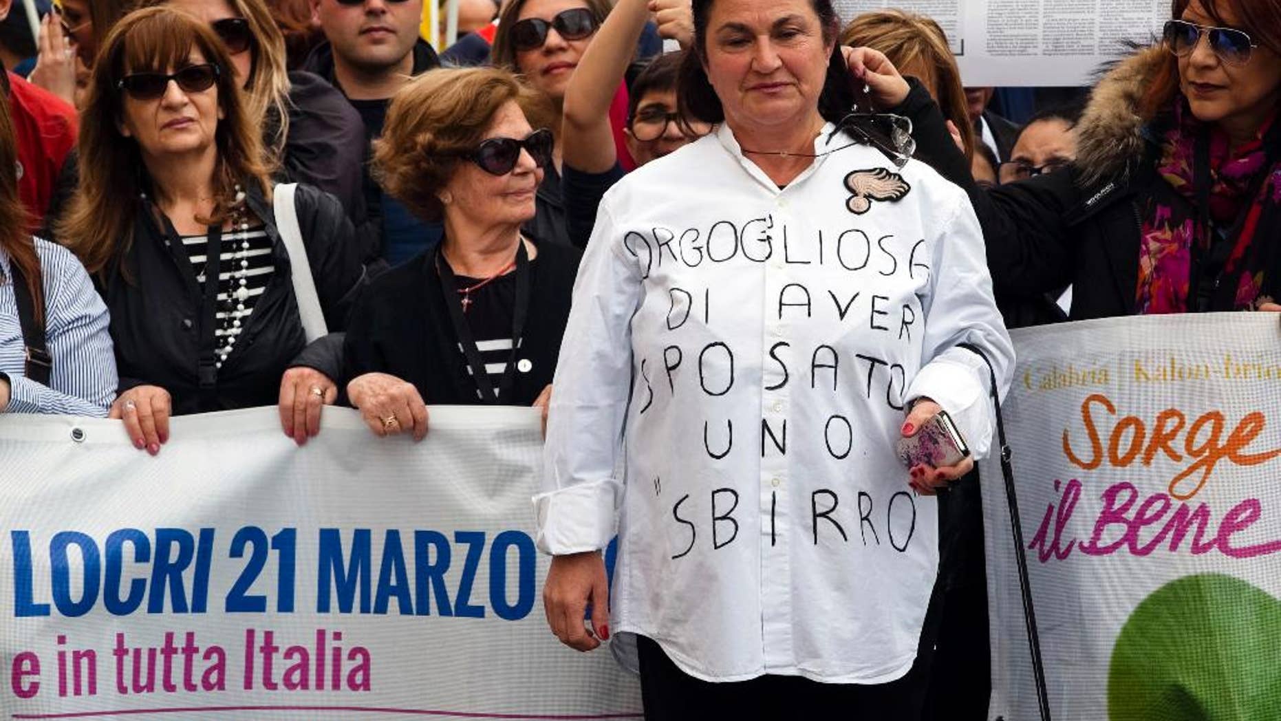 Rosetta Marino widow of Antonino, a Carabiniere officer killed in 1990, wears a T-shirt reading "I'm proud to have married a cop" during an anti mafia march in Locri, a base of the 'ndrangheta crime syndicate in Reggio Calabria, Southern Italy, Tuesday, March 21, 2017. On the eve of Tuesday's protest, vandals scrawled graffiti in the mafia stronghold of Locri calling Don Luigi Ciotti, a leading anti-mafia crusader, a cop and demanding "More work, fewer cops." (Marco Costantino/ANSA via AP)