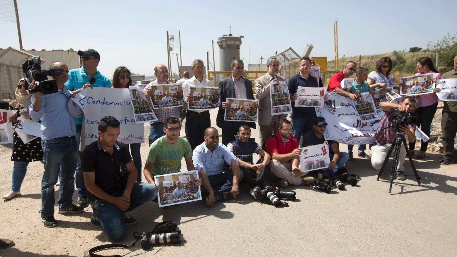 Palestinian journalists hold banners during a protest calling for the release of Palestinian journalist Omar Nazzal, who was arrested by Israeli authorities over the weekend, outside Ofer military prison near the West Bank city of Ramallah, Tuesday, April 26, 2016. (AP Photo/Majdi Mohammed)