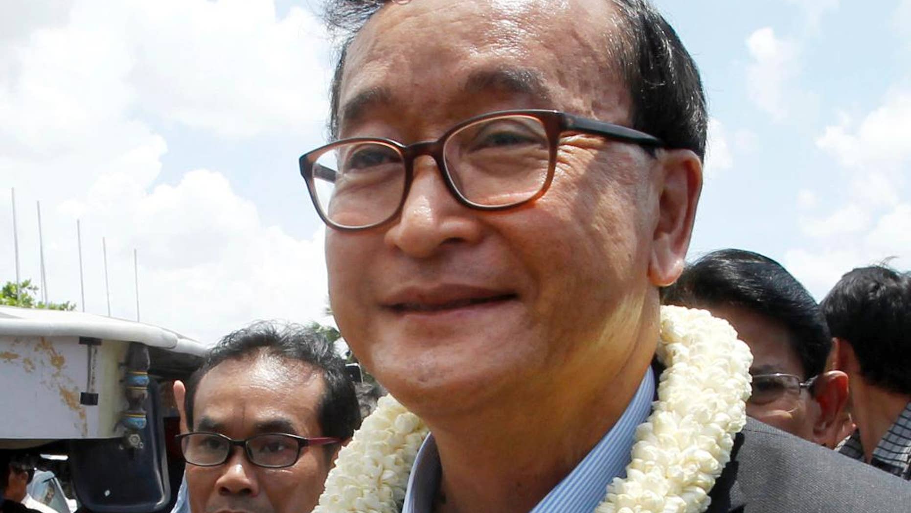 FILE - In this Aug. 16, 2015, file photo, Sam Rainsy, leader of the opposition Cambodia National Rescue Party, greets his party supporters upon his arrival at Phnom Penh International Airport in Phnom Penh, Cambodia. The Phnom Penh Municipal Court on Tuesday, Nov. 8, 2016, found Sam Rainsy, country's exiled opposition leader, guilty of defamation for alleging that a senior government official sought to inflate Prime Minister Hun Sen's online popularity by buying "likes" for his Facebook page. (AP Photo/Heng Sinith, File)